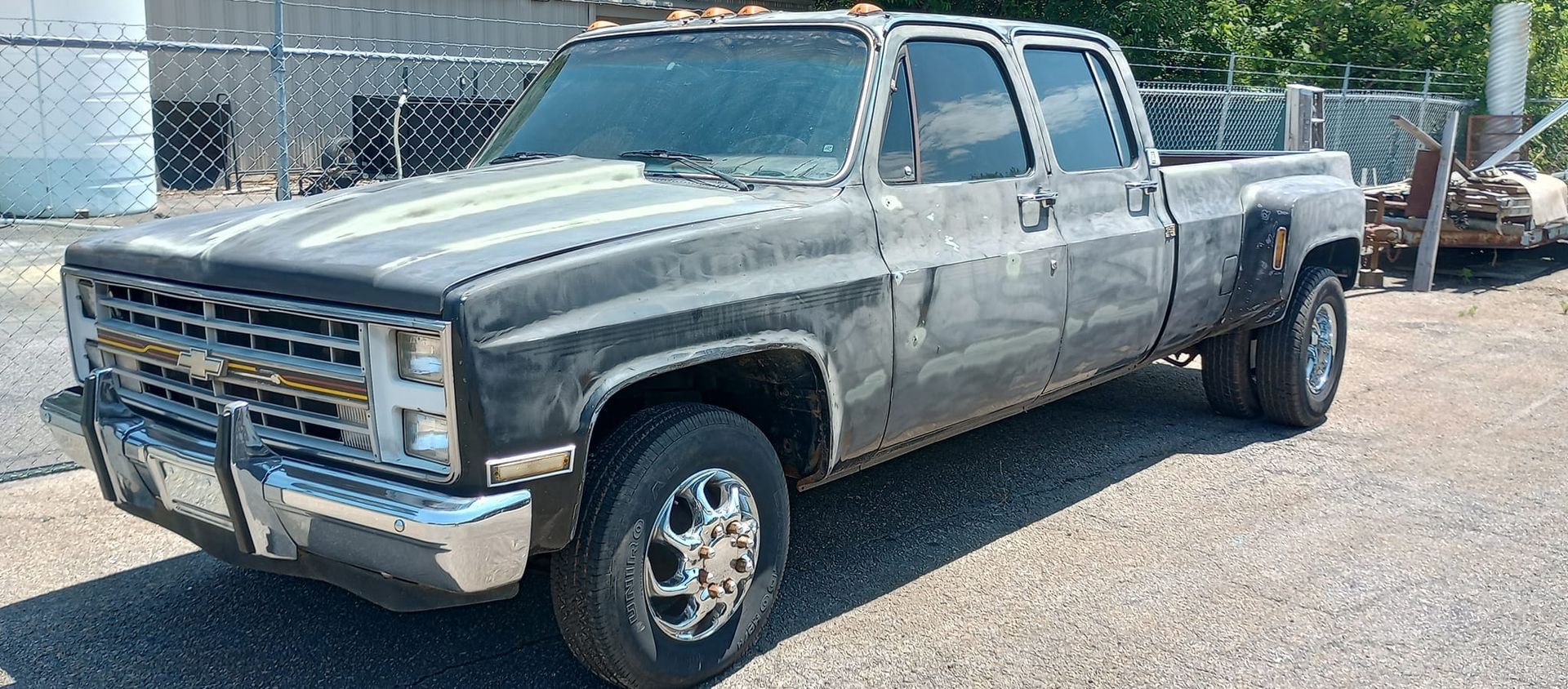 A dirty truck is parked in a gravel lot.