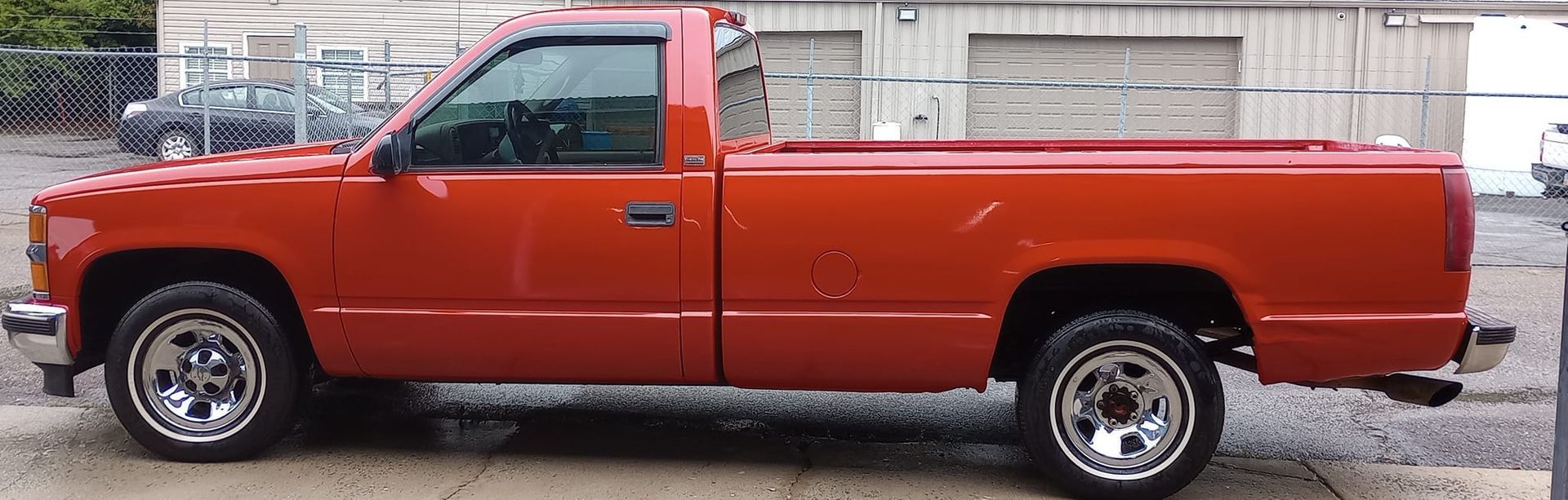 A red truck is parked in front of a garage.