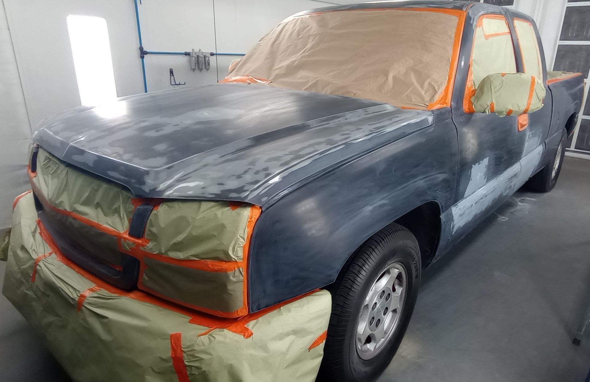 A truck is being painted in a paint booth.