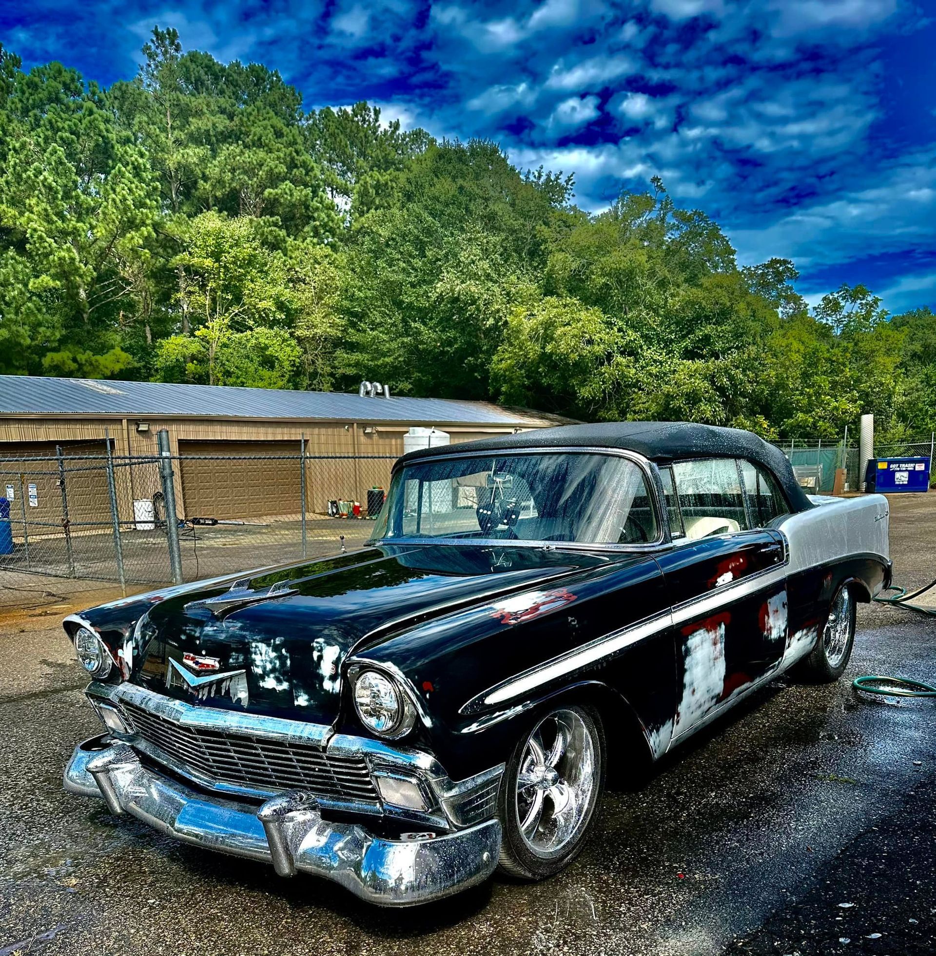A black and white classic car is parked in a parking lot.