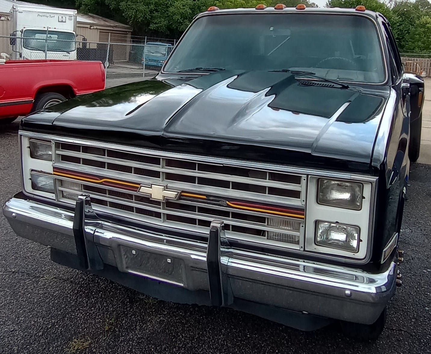 A black chevrolet truck is parked next to a red truck