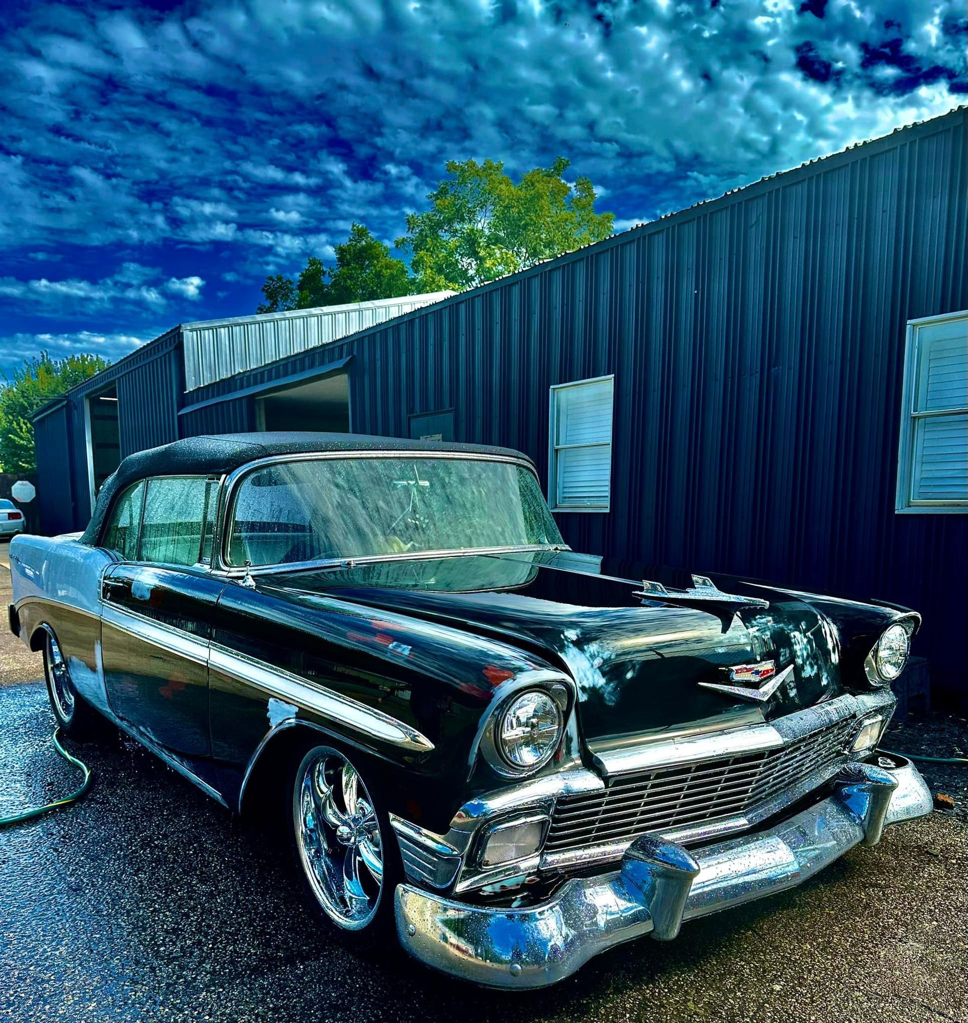 A black classic car is parked in front of a building.