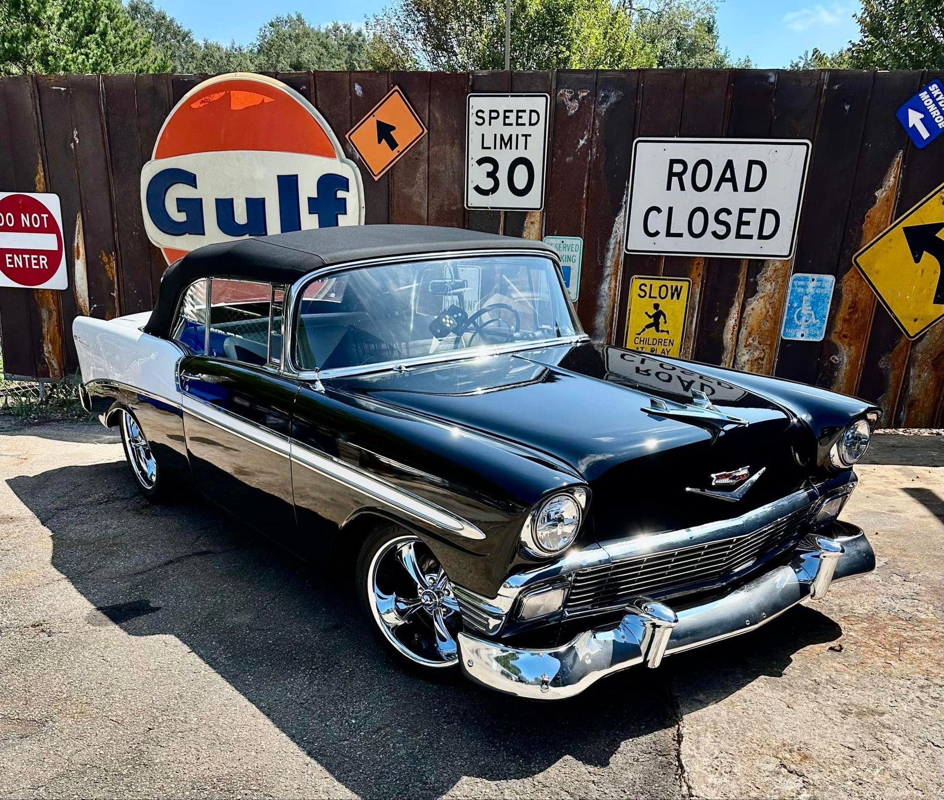 A black and white car is parked in front of a gulf sign