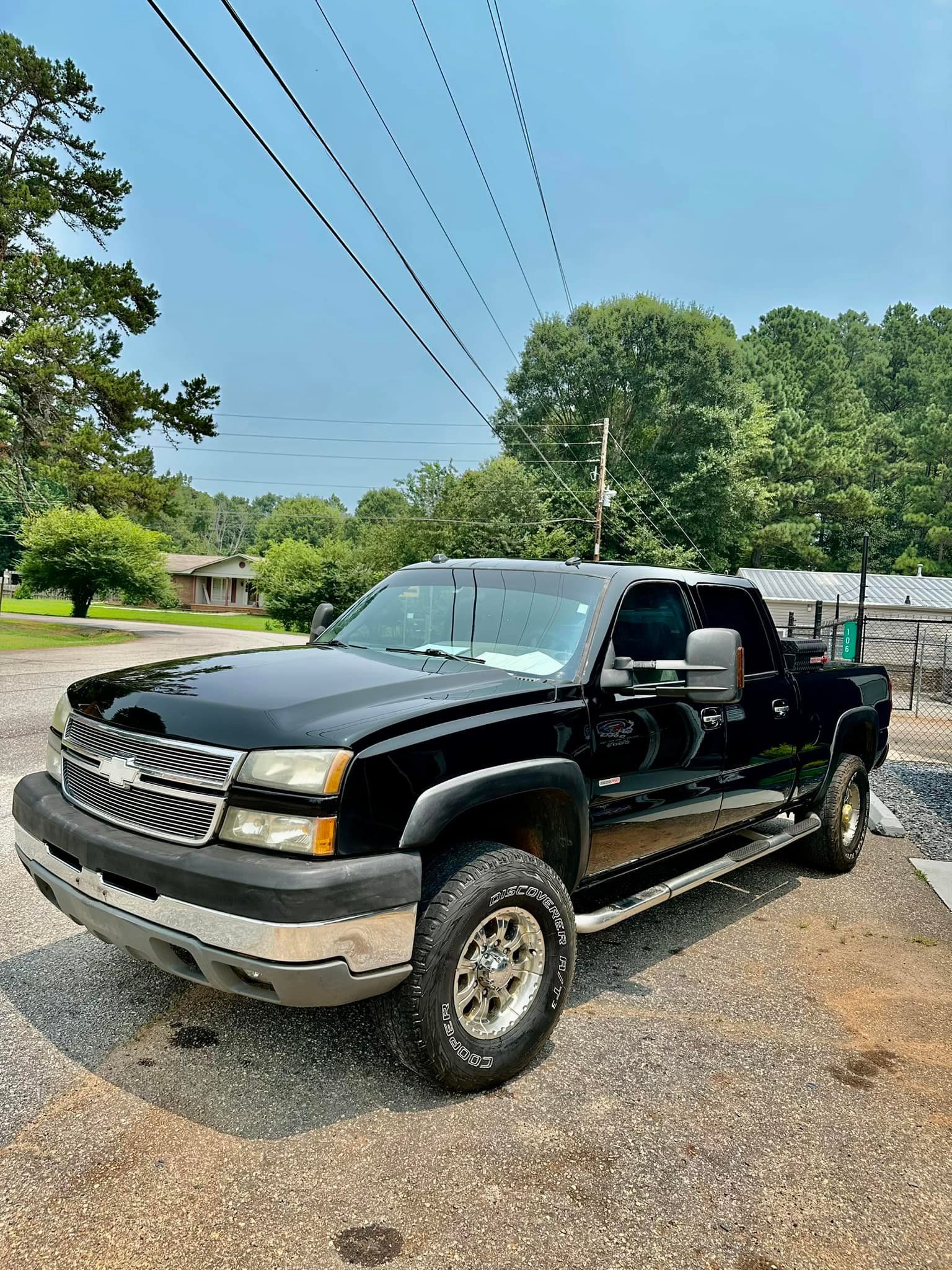 A black pickup truck is parked in a gravel lot.