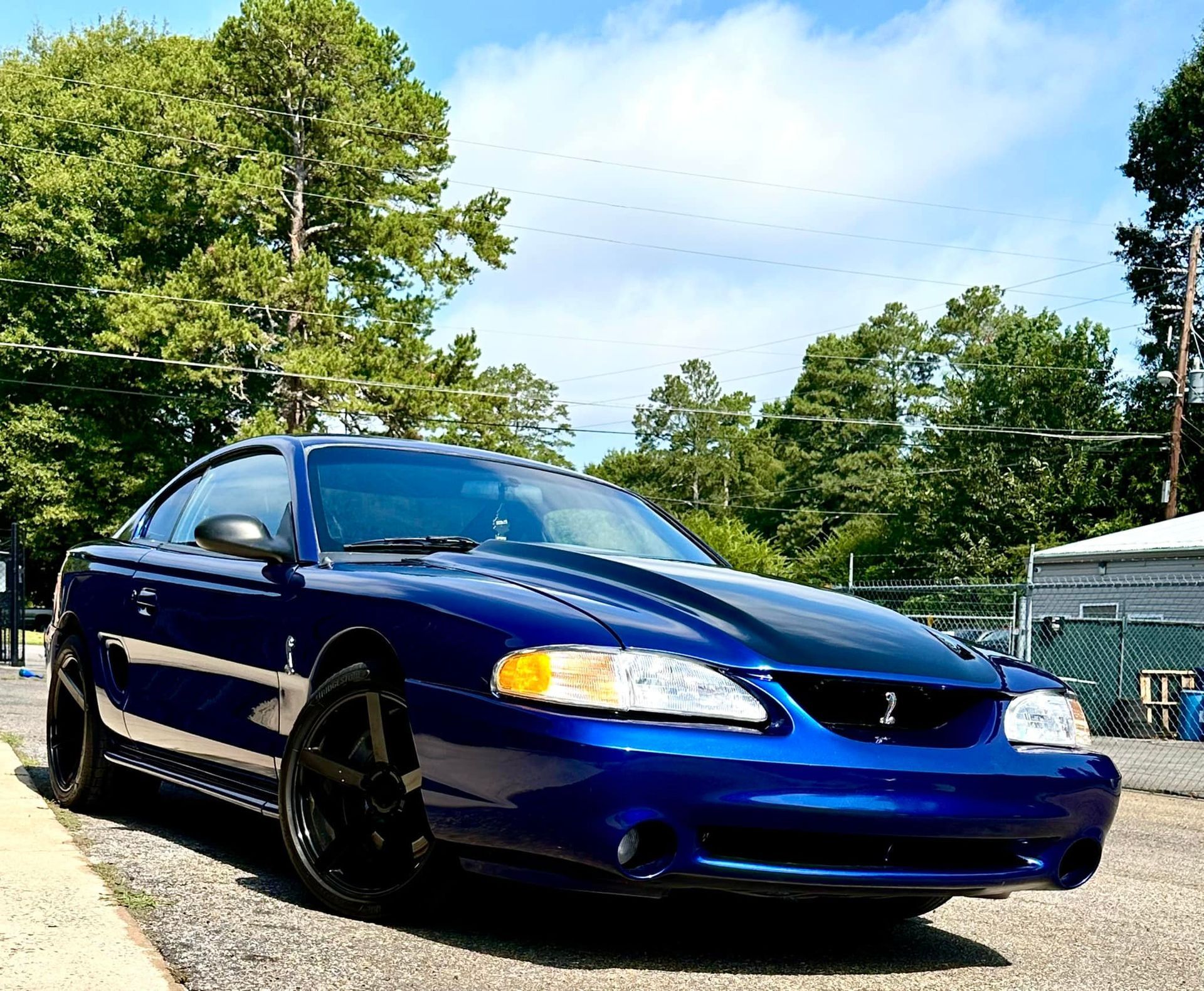 A blue mustang is parked on the side of the road