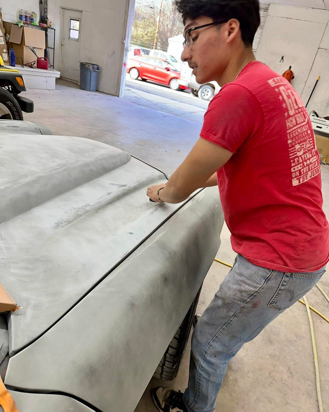 A man in a red shirt is working on a car