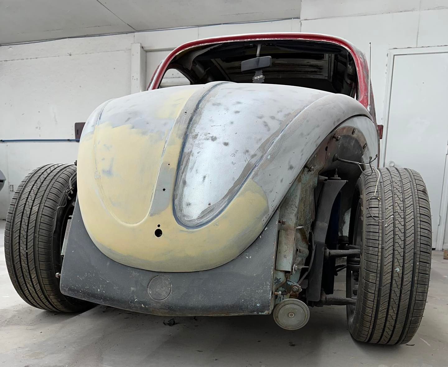 A volkswagen beetle is being restored in a garage