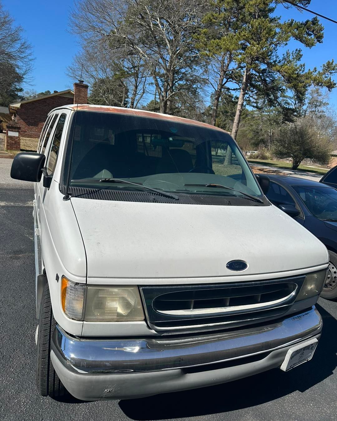 A white van is parked in a parking lot in front of a house.