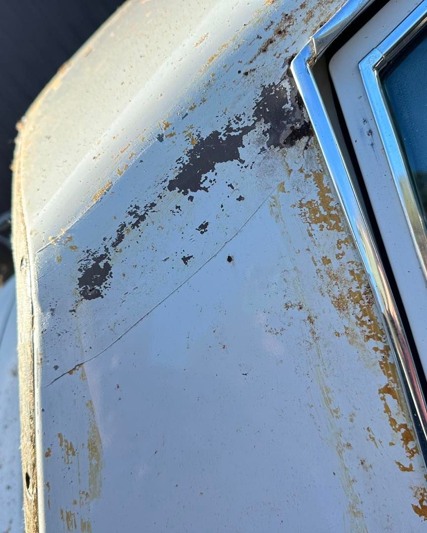 A close up of a white car with rust on it.