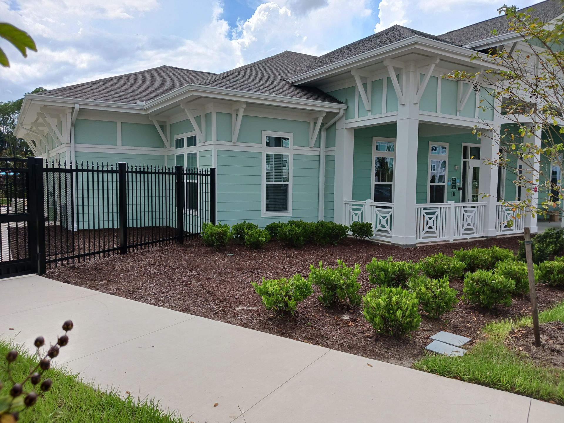 A large house with a porch and a fence in front of it.