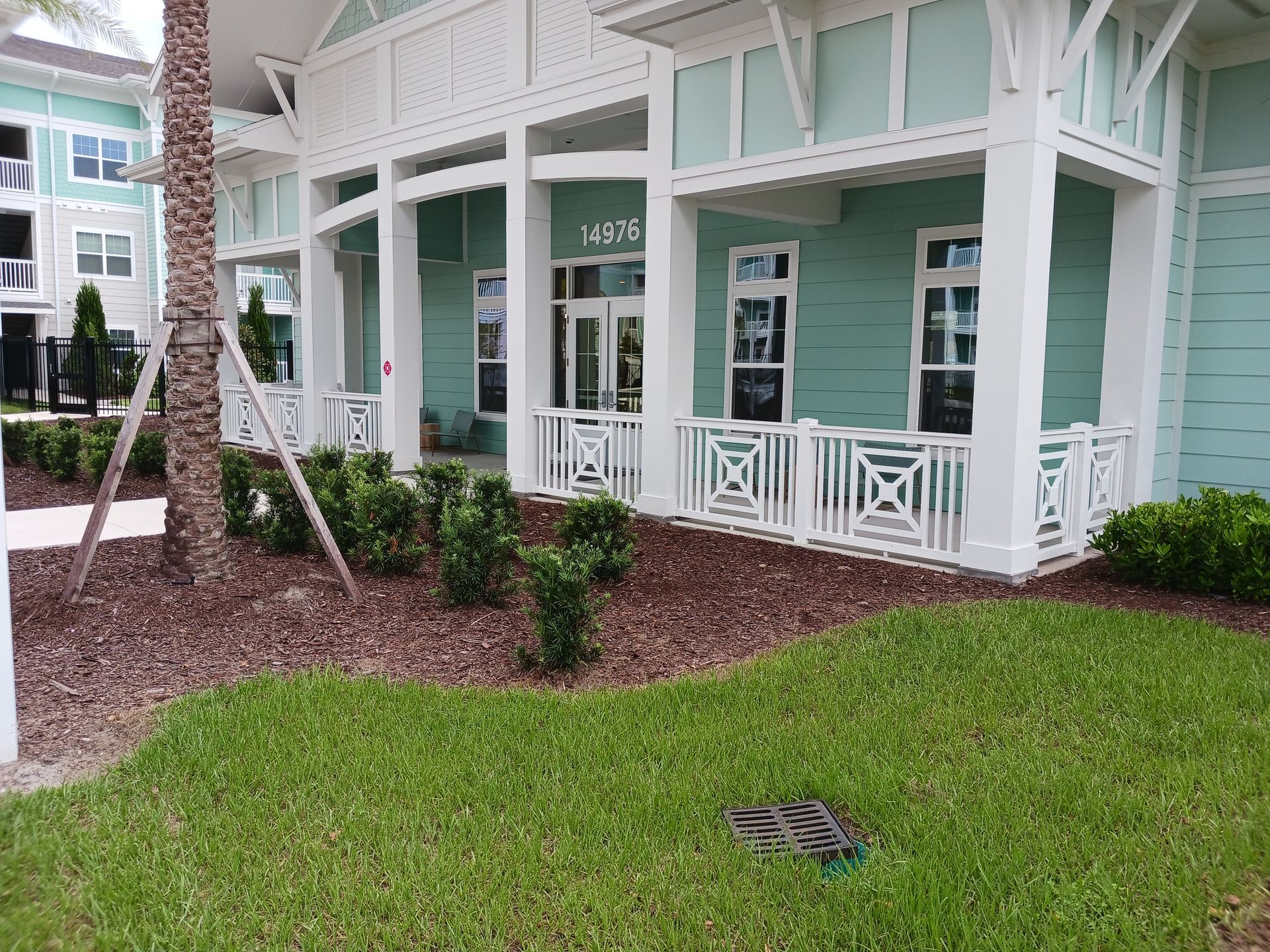 A blue and white house with a porch and a lawn in front of it.