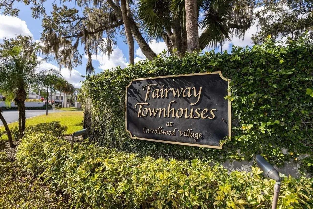 Farway Townhouses sign amid green hedges and palm trees on a sunny street