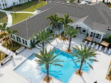 Aerial view of a luxury resort pool courtyard with palm trees and white lounge chairs
