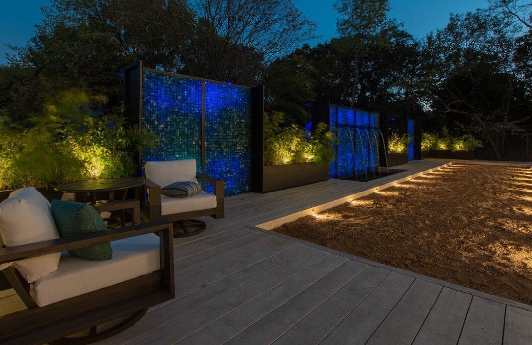 A patio with chairs and a patio at night.- Crowders Landscaping