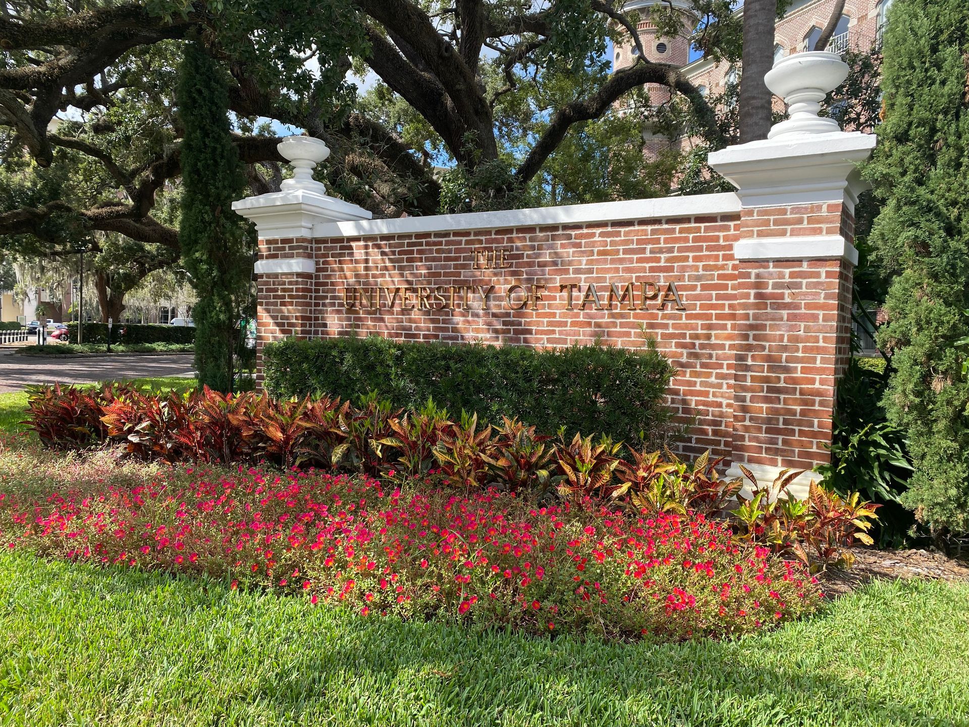 A brick wall with flowers in front of it in a park.