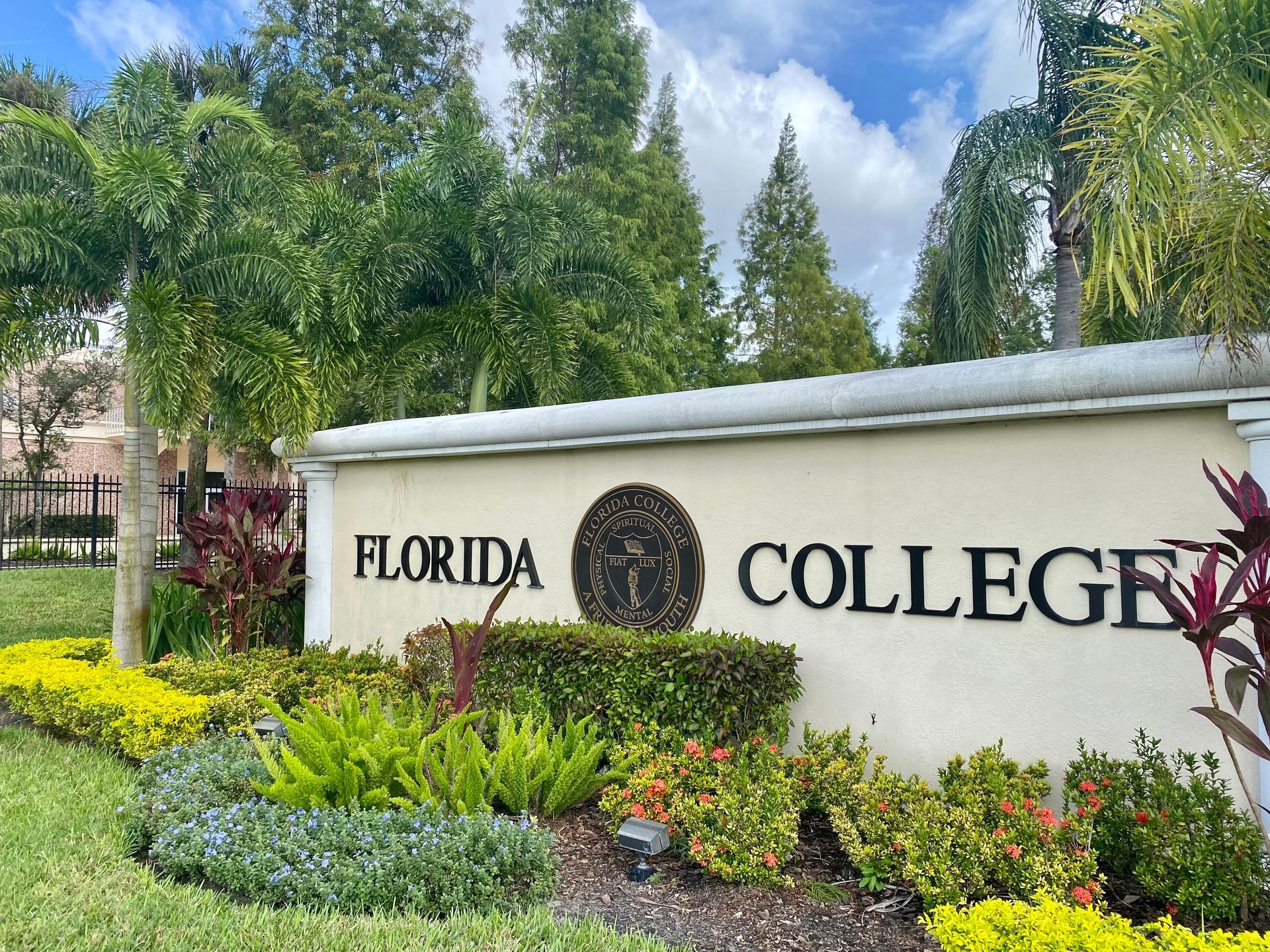 A sign for florida college is surrounded by plants and trees