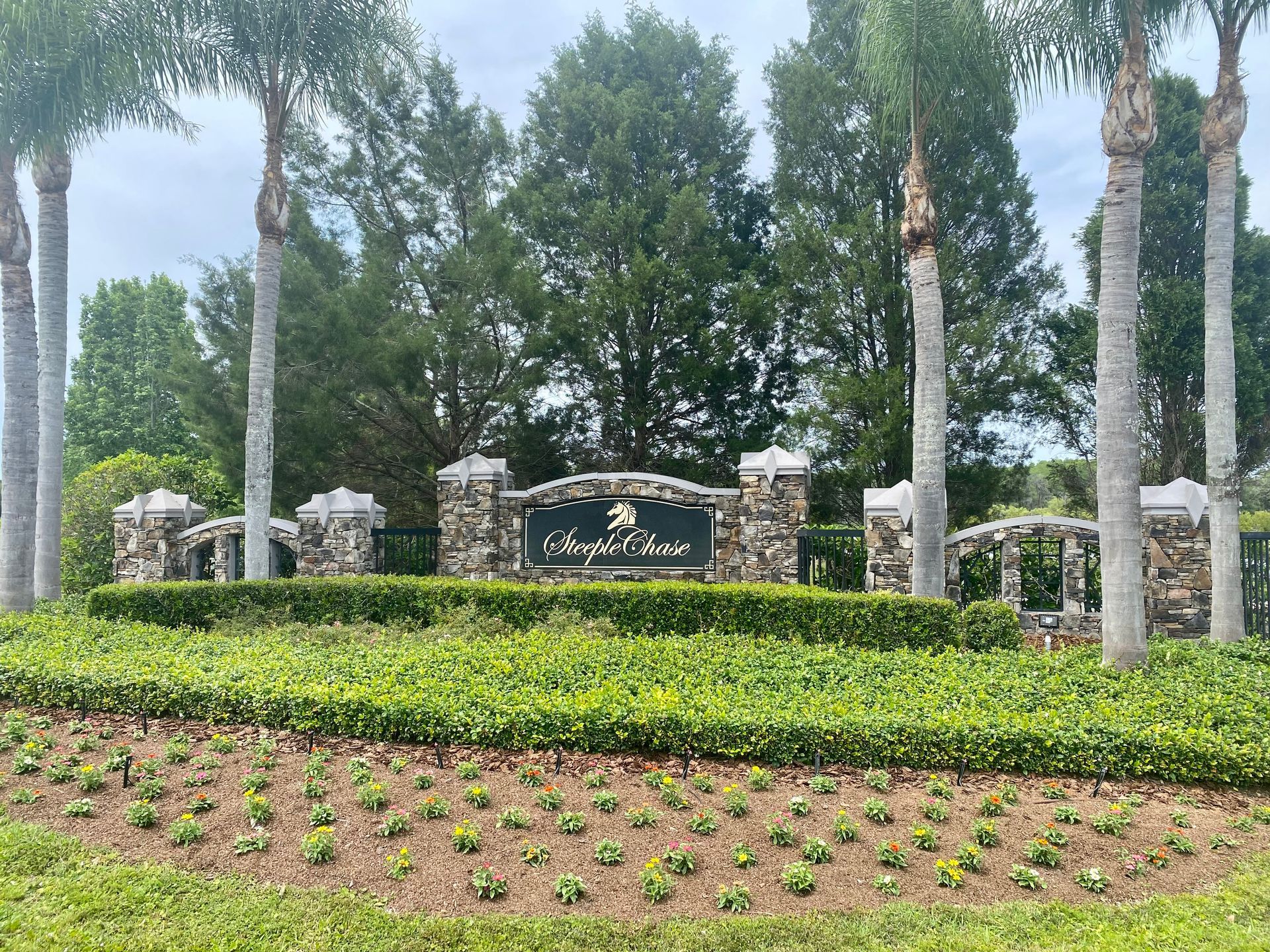 A sign in the middle of a lush green field with palm trees in the background.