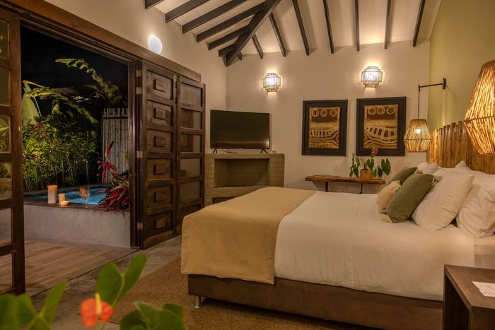 Un dormitorio con una cama king size, sillas, mesa y televisión.