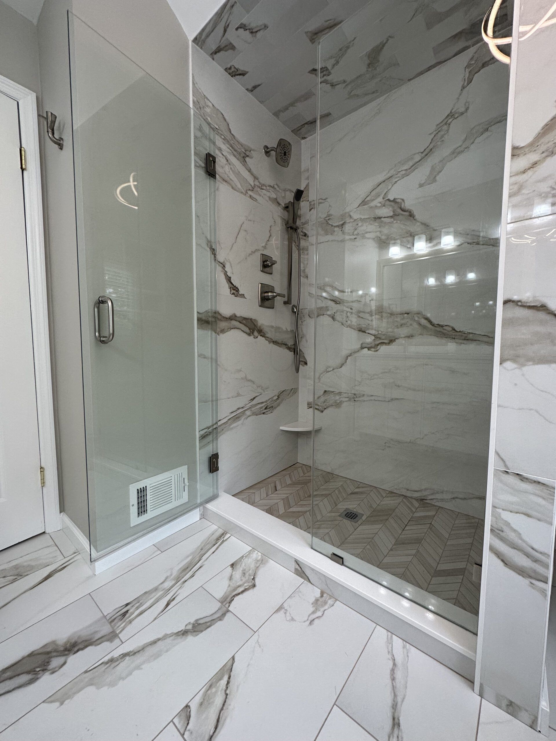 Luxury marble-tiled bathroom with glass shower enclosure and built-in shelving
