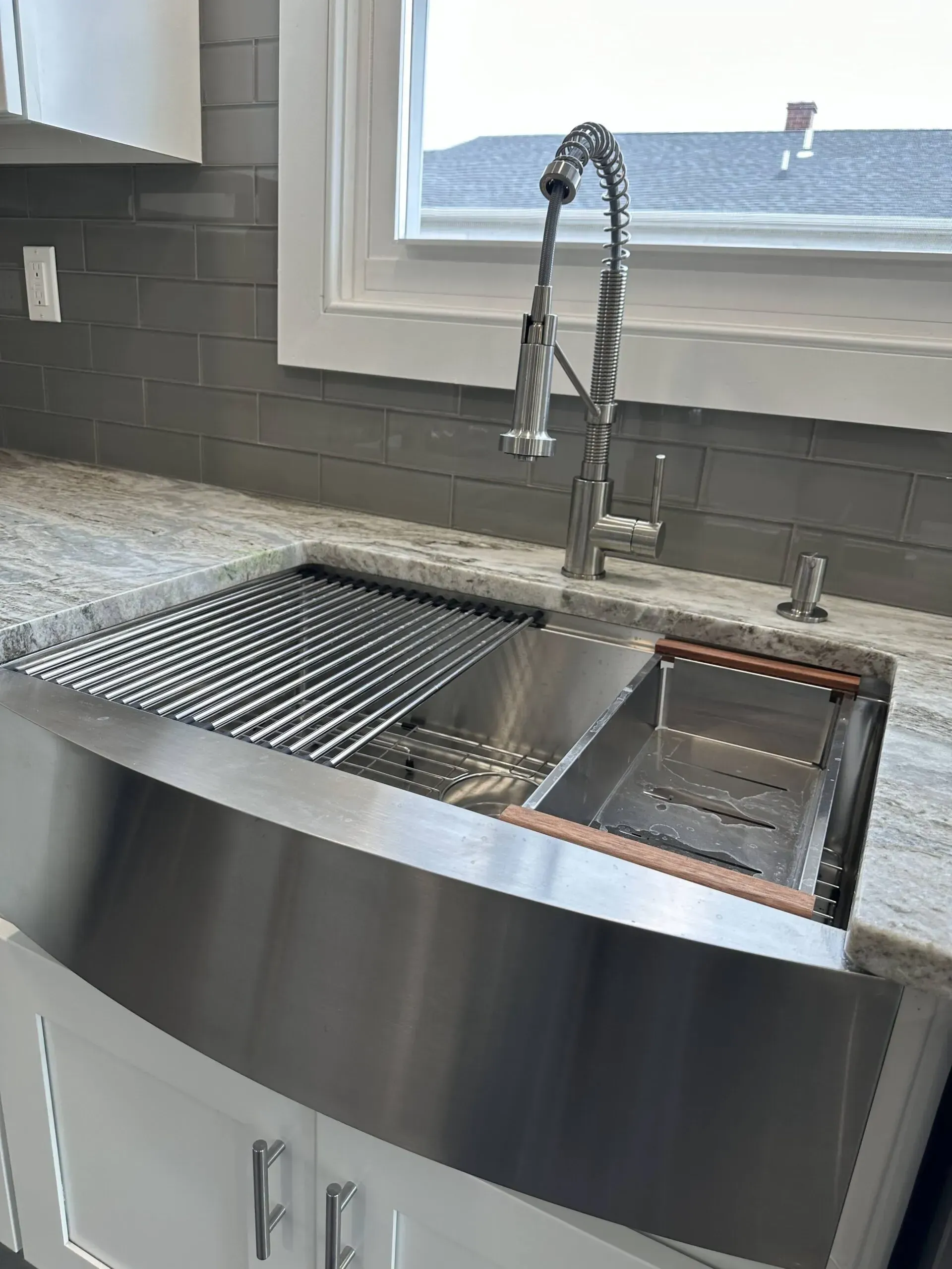 Modern kitchen sink with tall faucet, drying rack, and window overlooking water