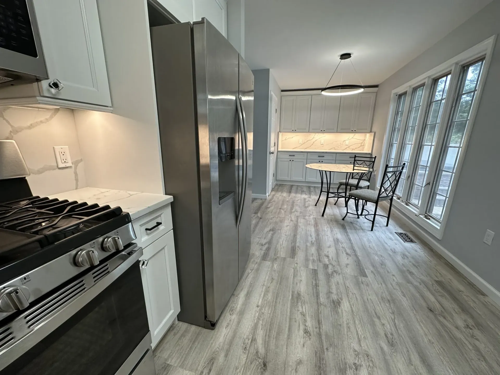 Modern kitchen and dining area with stainless steel appliances, light wood floors, and glass doors to a patio