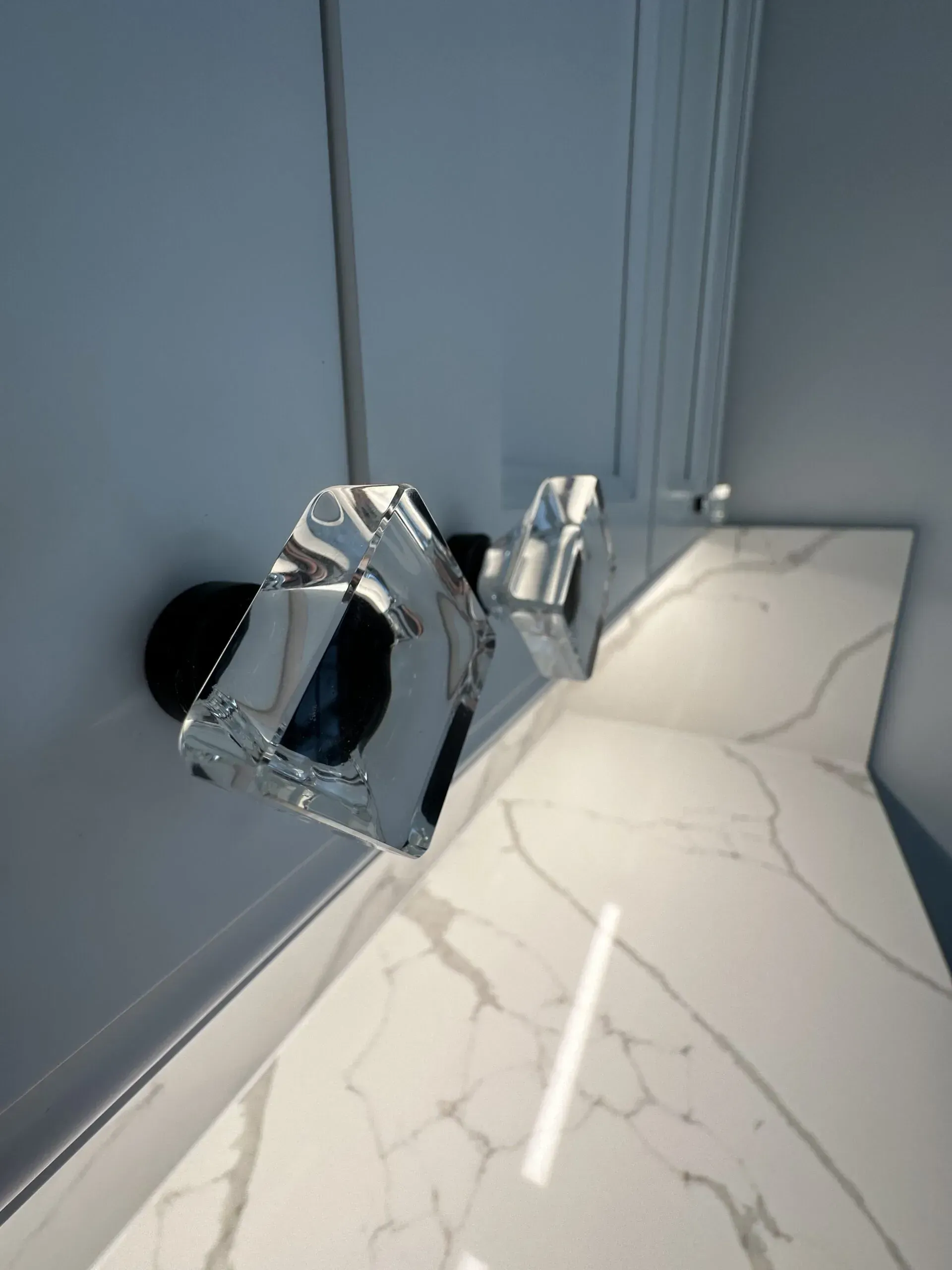 Crushed silver canister on a white marble floor beside a blue wall and black round object