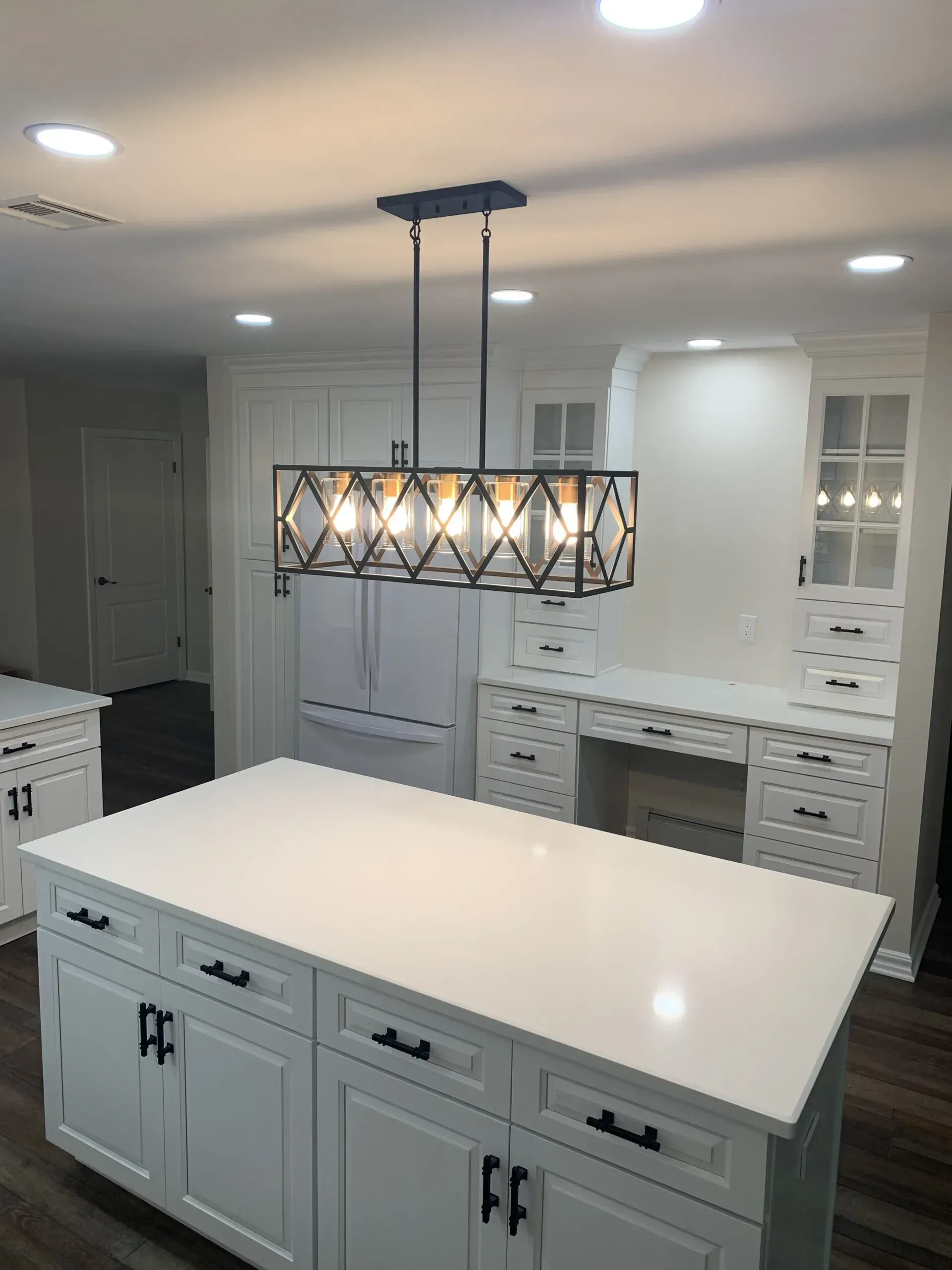 Modern kitchen with a white island and pendant light, gray cabinets, and built-in oven