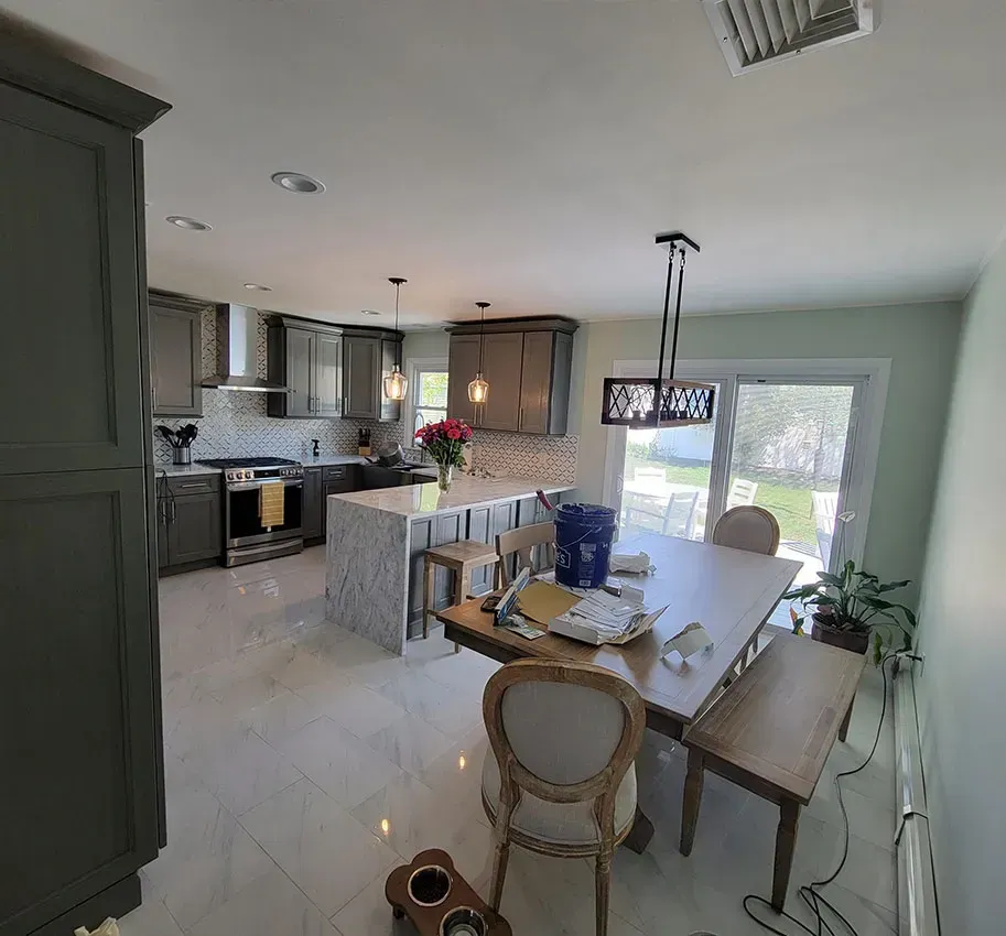 Bright kitchen and dining area with white cabinets, island seating, and sliding glass door.