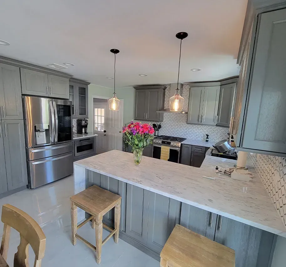 Bright modern kitchen with gray cabinets, white island, stainless appliances, and pink flowers in a vase