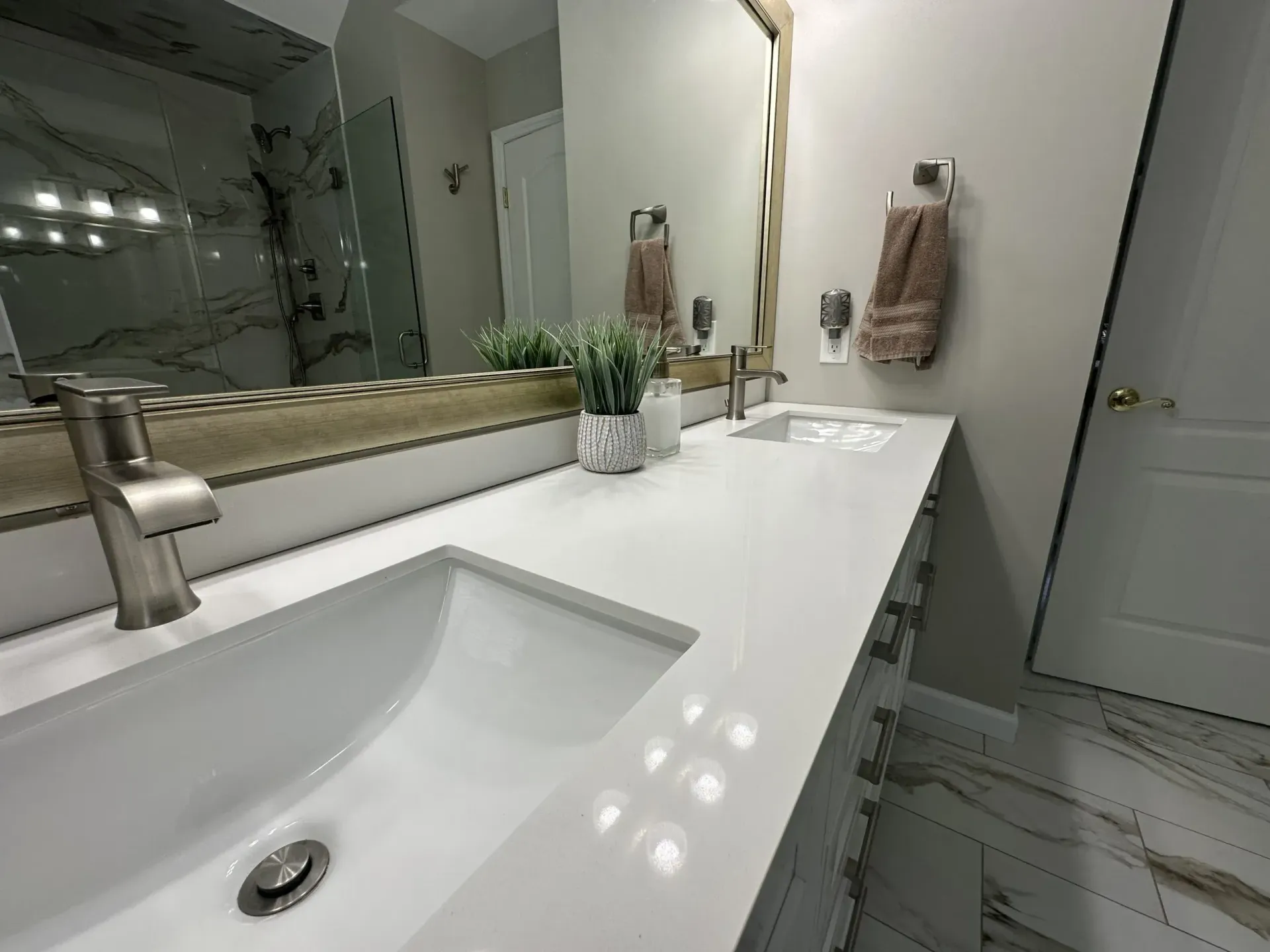A bathroom with a sink , mirror and towels hanging on the wall.