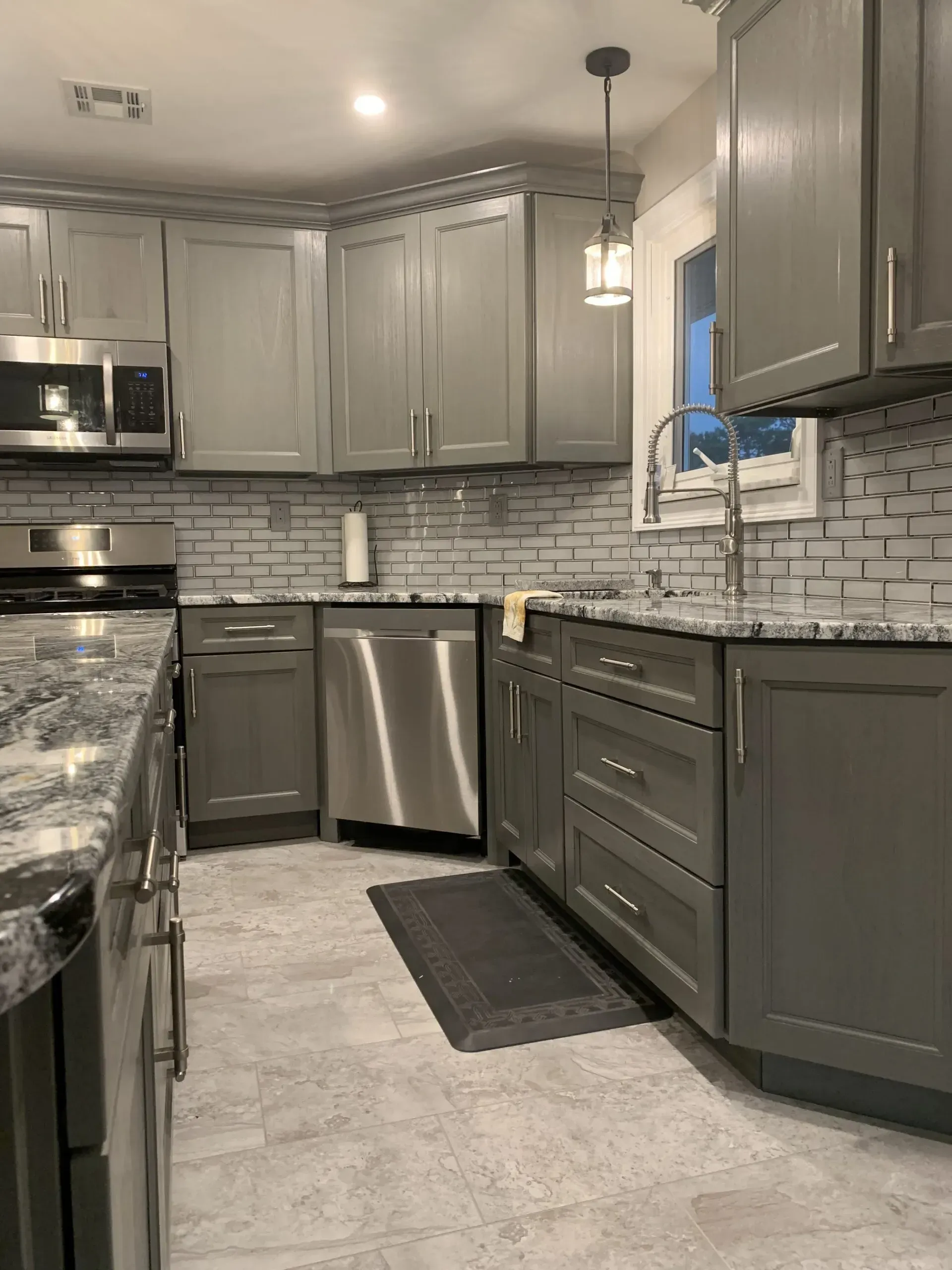 Modern kitchen with gray cabinets, stainless steel appliances, and a mosaic tile backsplash