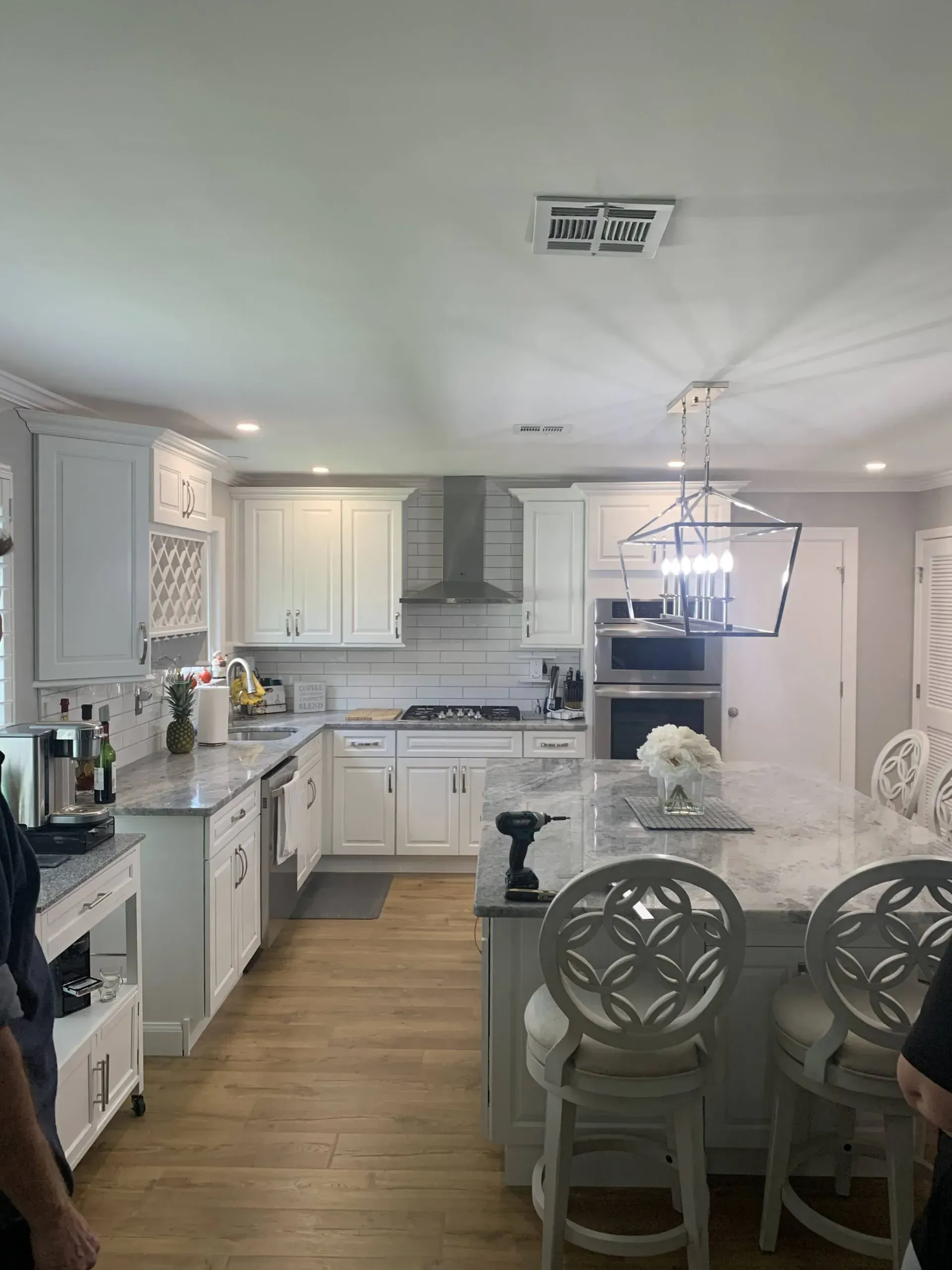Bright white kitchen and dining area with island, wood floors, and chandelier lighting