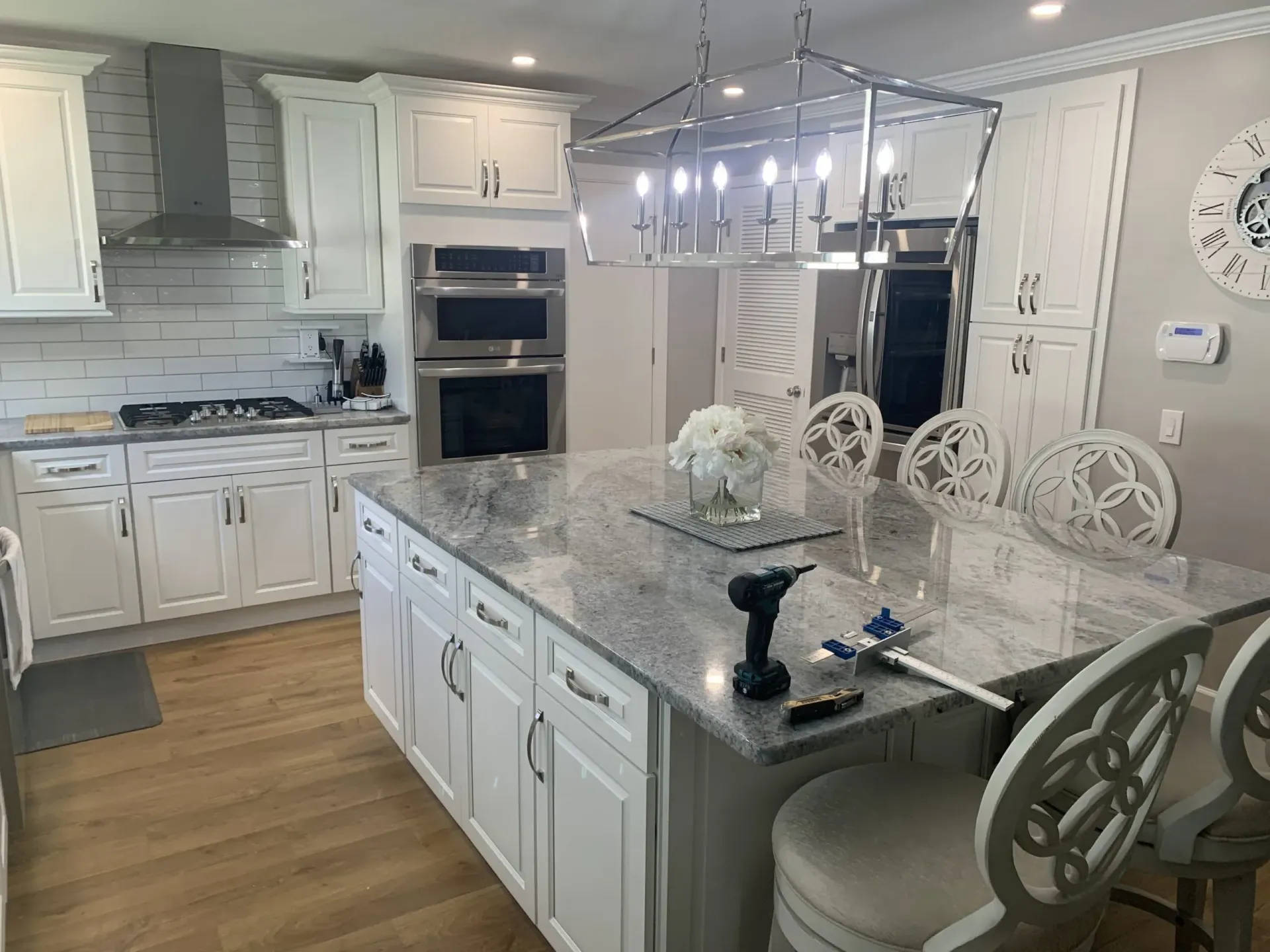 Bright modern kitchen with white cabinets, marble island, and chandelier lighting