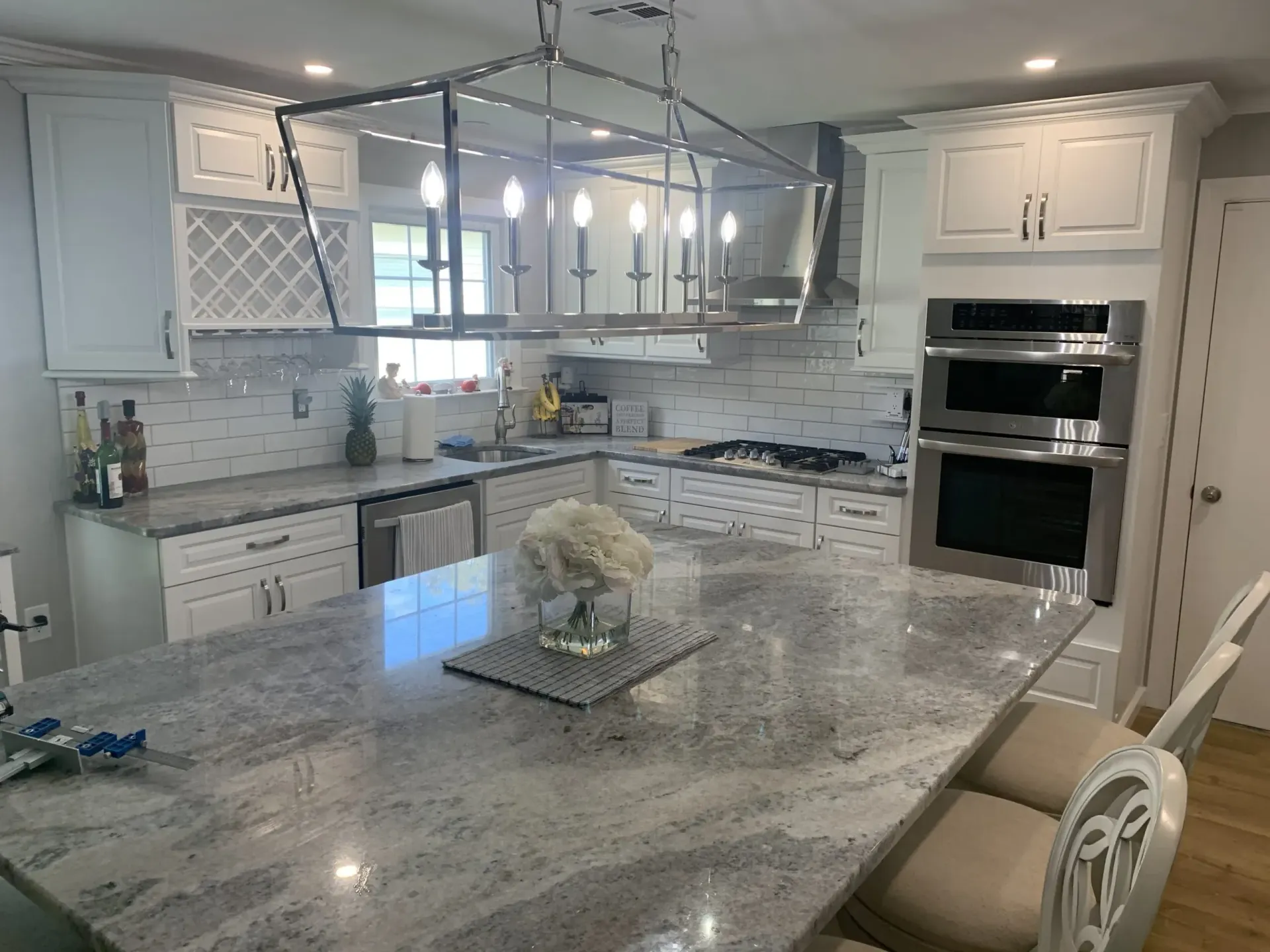 Bright modern kitchen with gray marble island, white cabinets, and stainless steel appliances