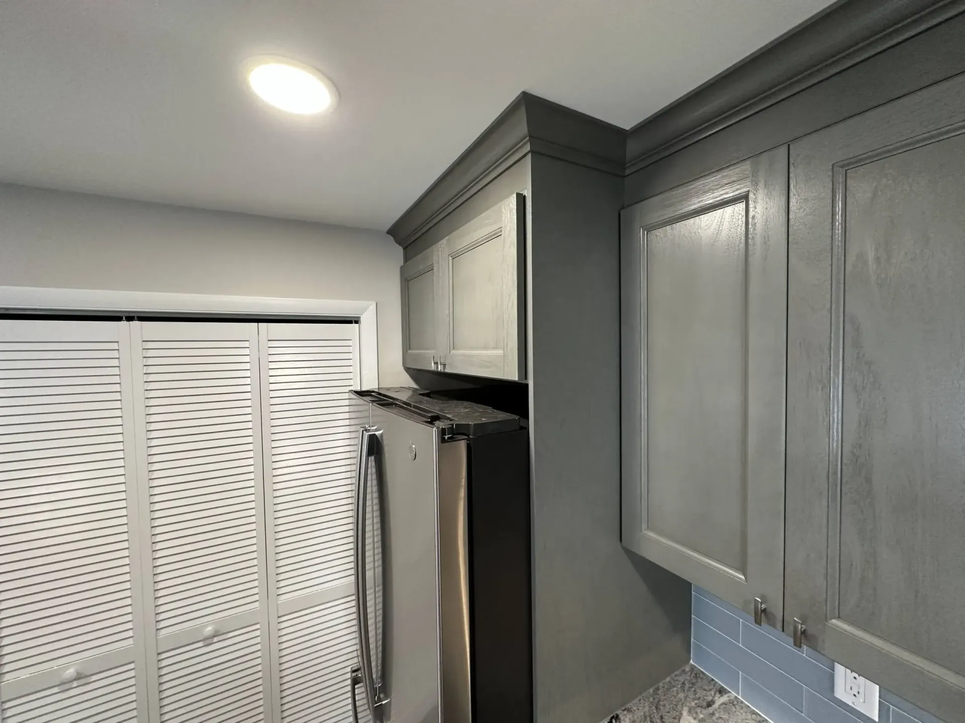 Gray kitchen cabinets and white louvered closet doors in a compact interior corner.