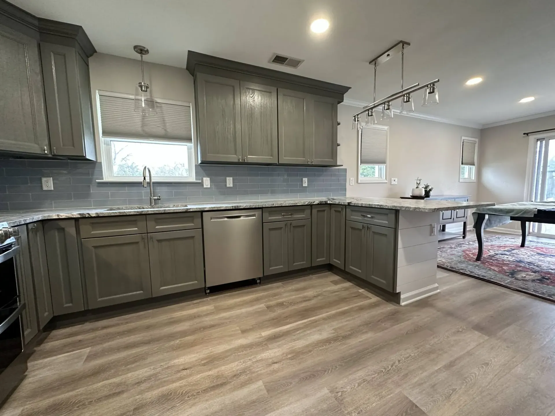 Modern kitchen with gray cabinets, stainless appliances, white island, and light wood flooring