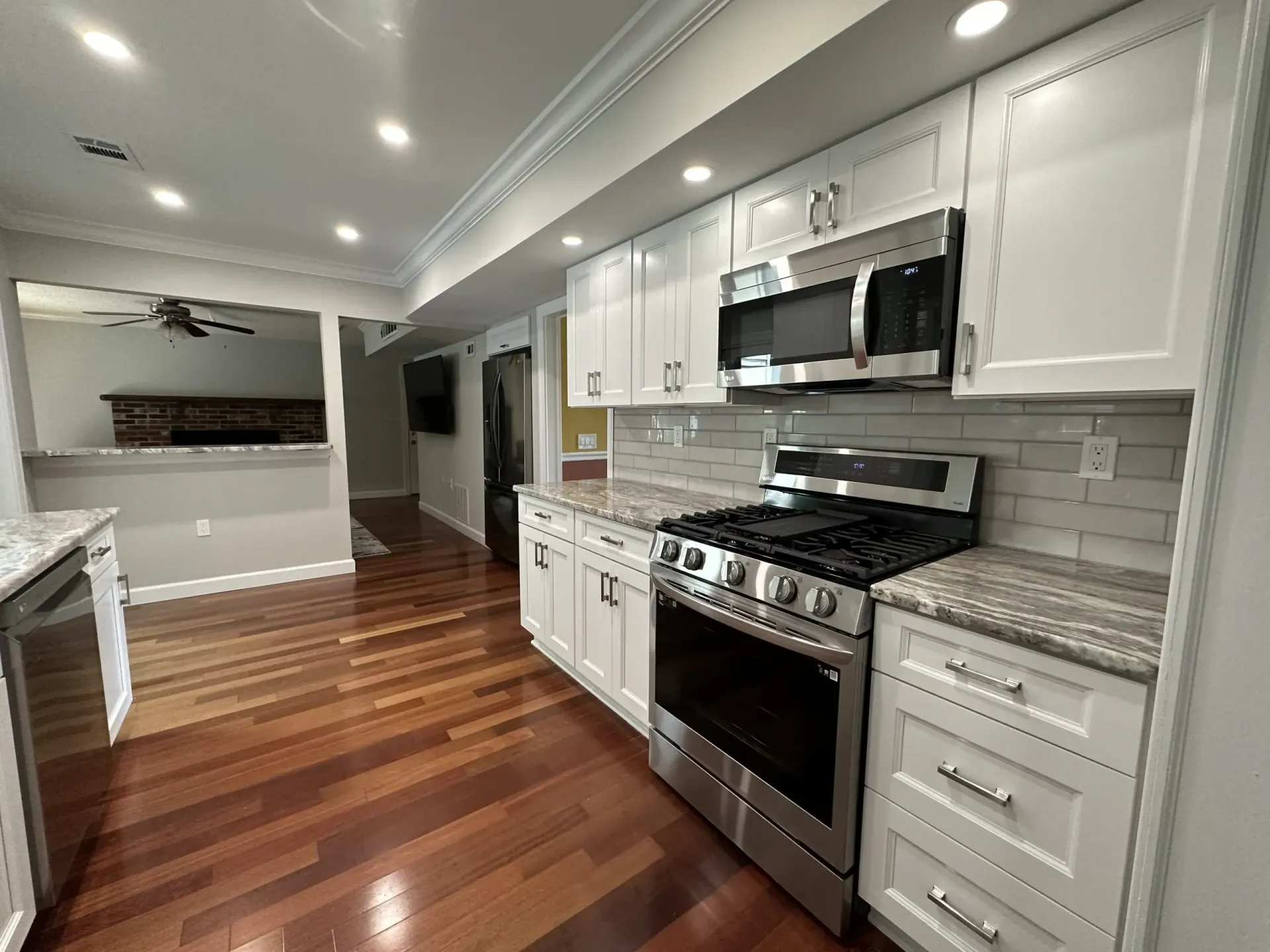 Bright modern kitchen with white cabinets, stainless appliances, and wood floors