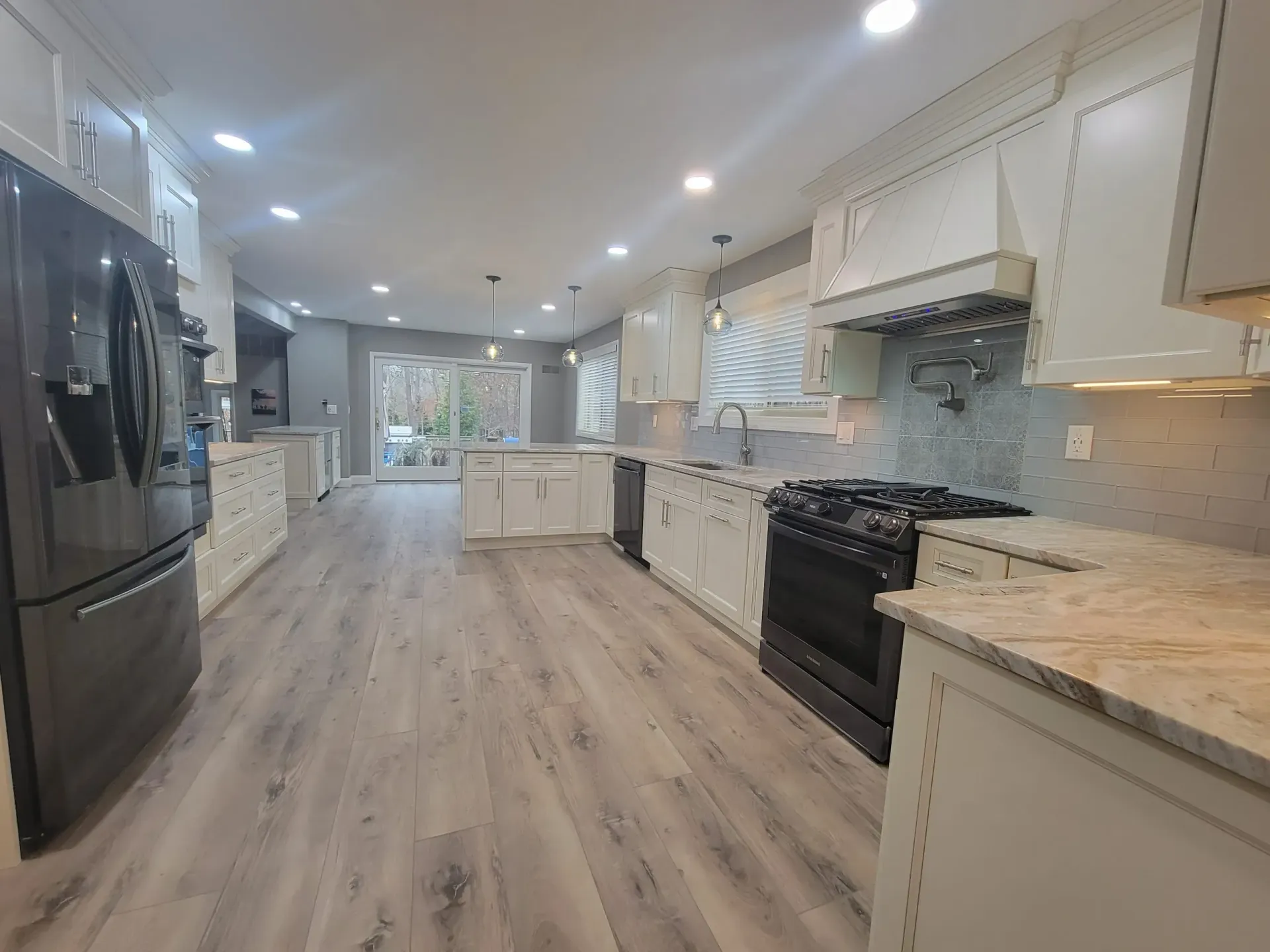 Bright modern kitchen with white cabinets, stainless appliances, granite counters, and wood-look flooring