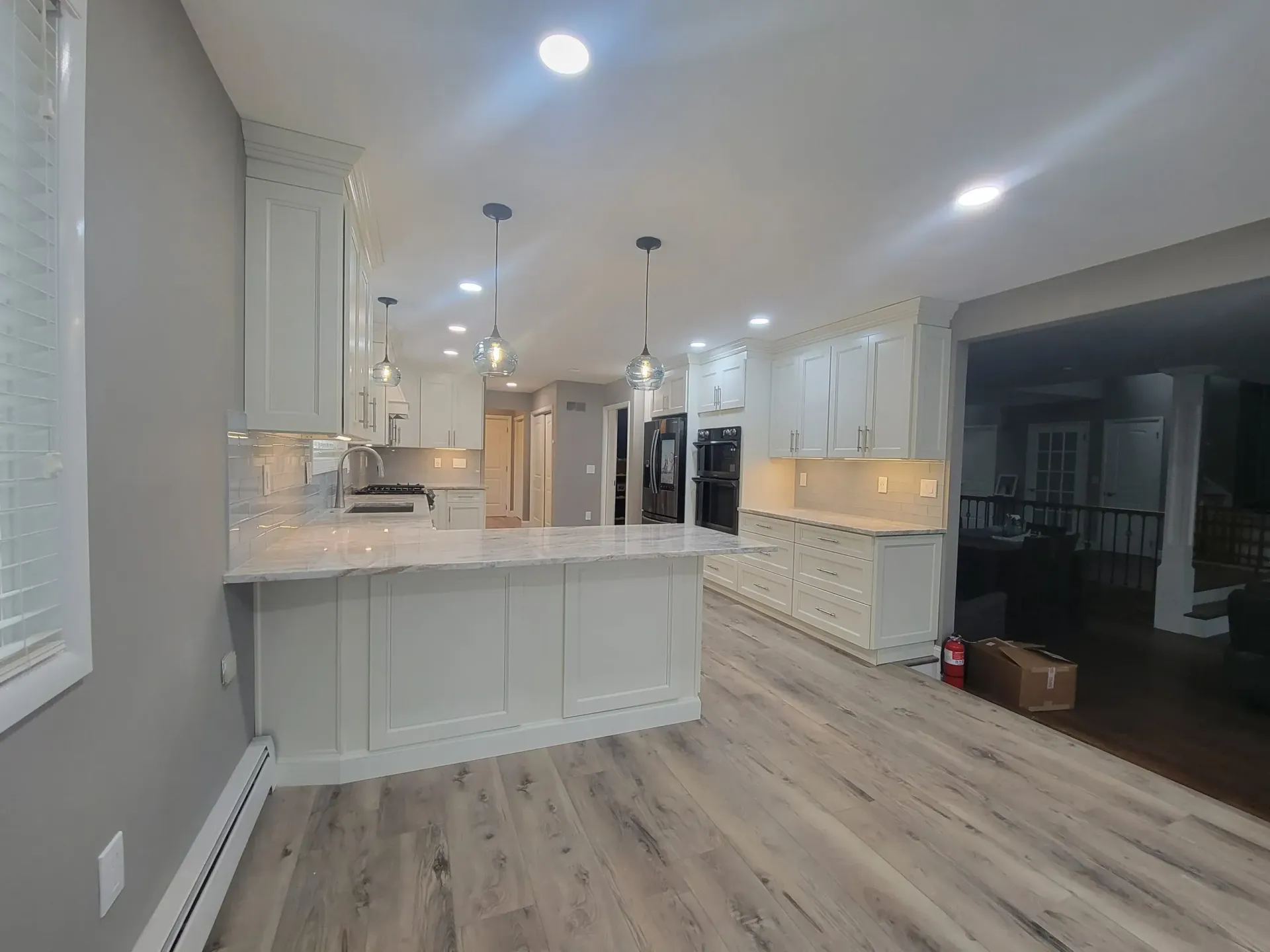 Bright open-plan kitchen with white cabinets, island, and wood-look flooring