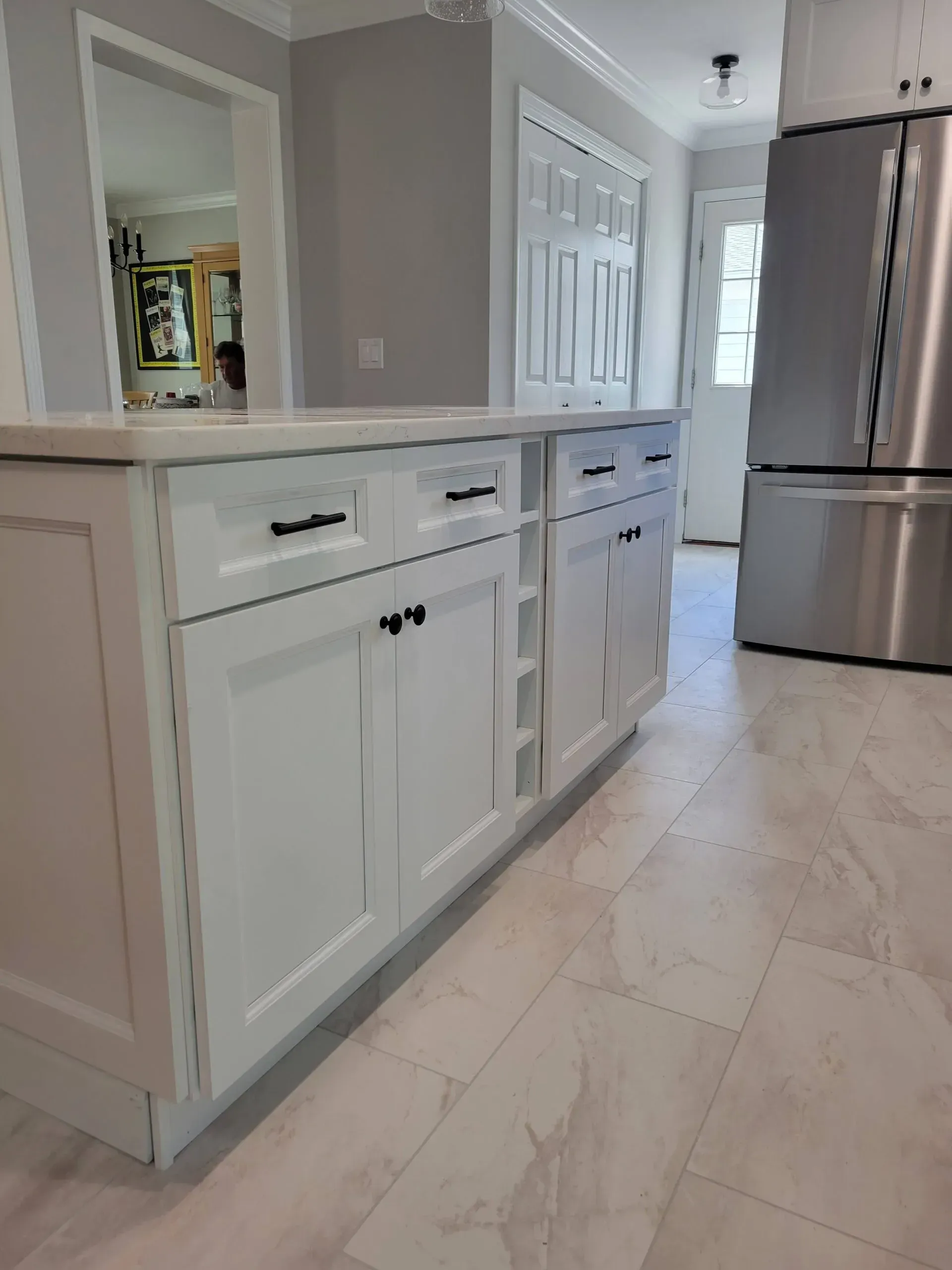 Bright kitchen with white cabinets, light tile floor, and stainless steel refrigerator.