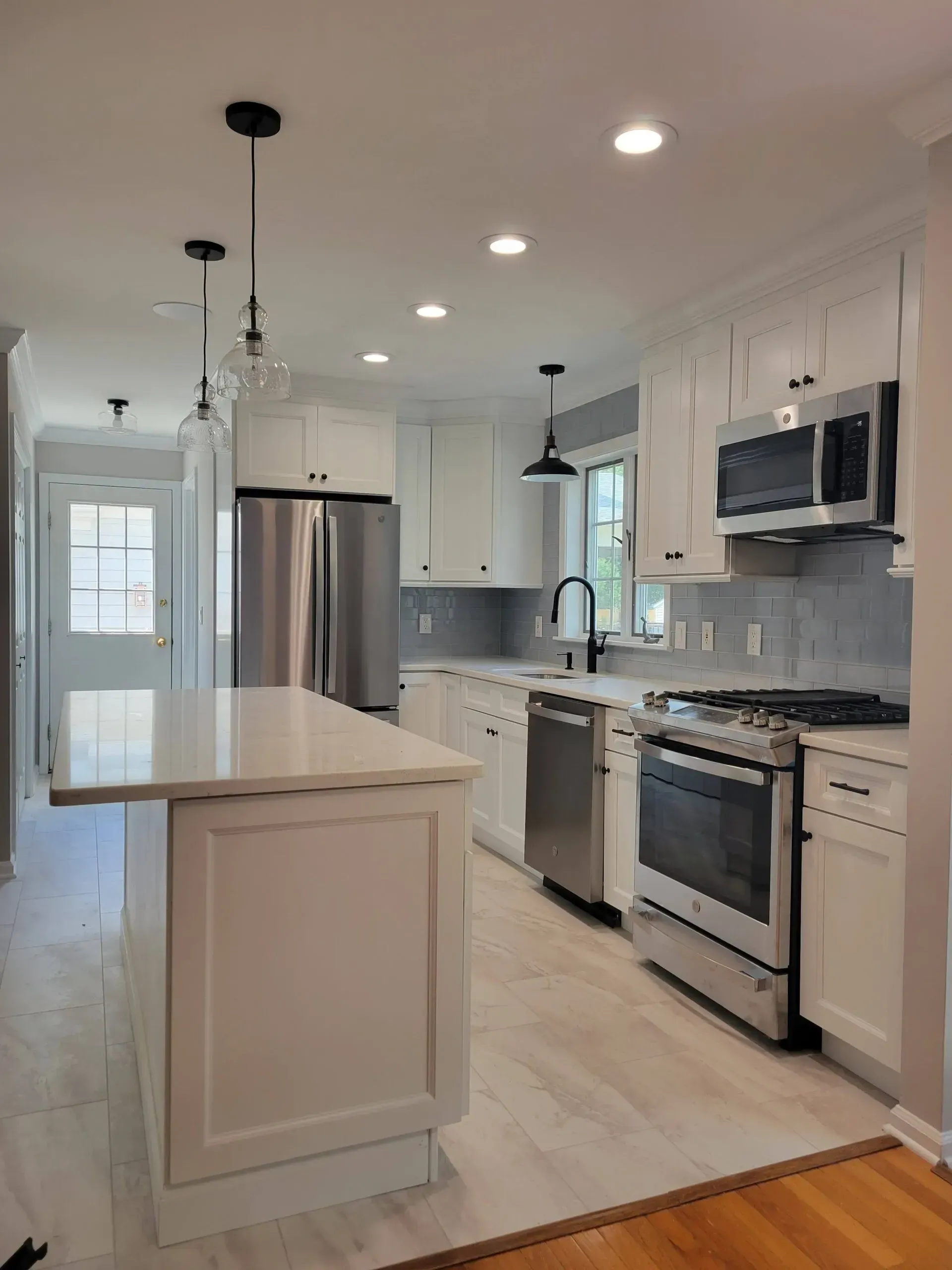 Bright modern kitchen with white cabinets, stainless steel appliances, island, and pendant lights