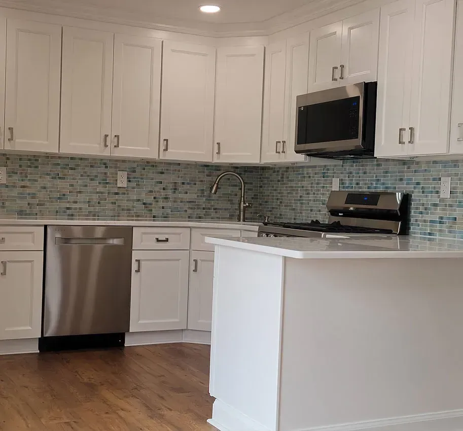 Bright modern kitchen with white cabinets, stainless appliances, and teal mosaic backsplash
