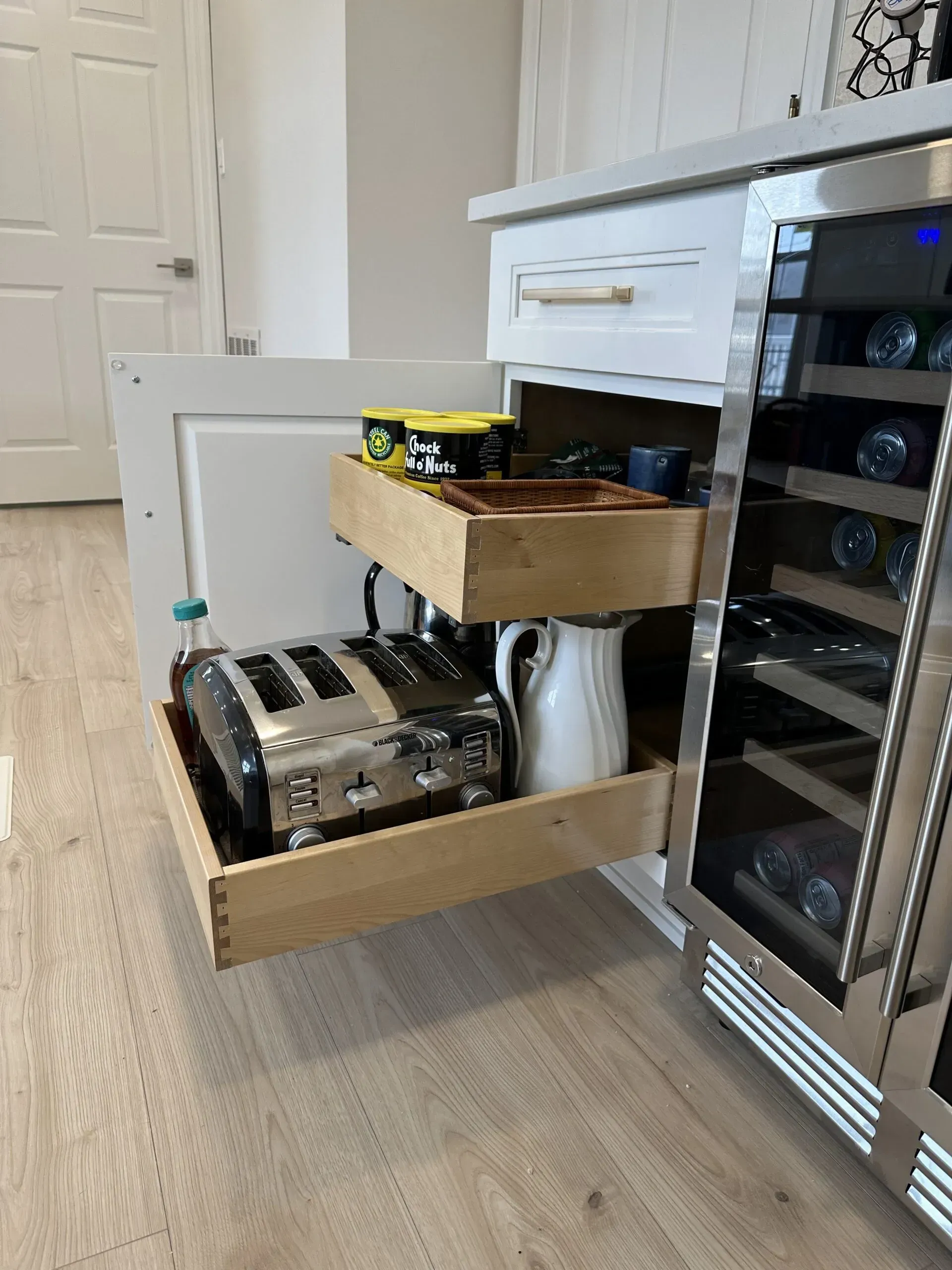 Open refrigerator drawer with bread, bottles, and packaged food in a kitchen.