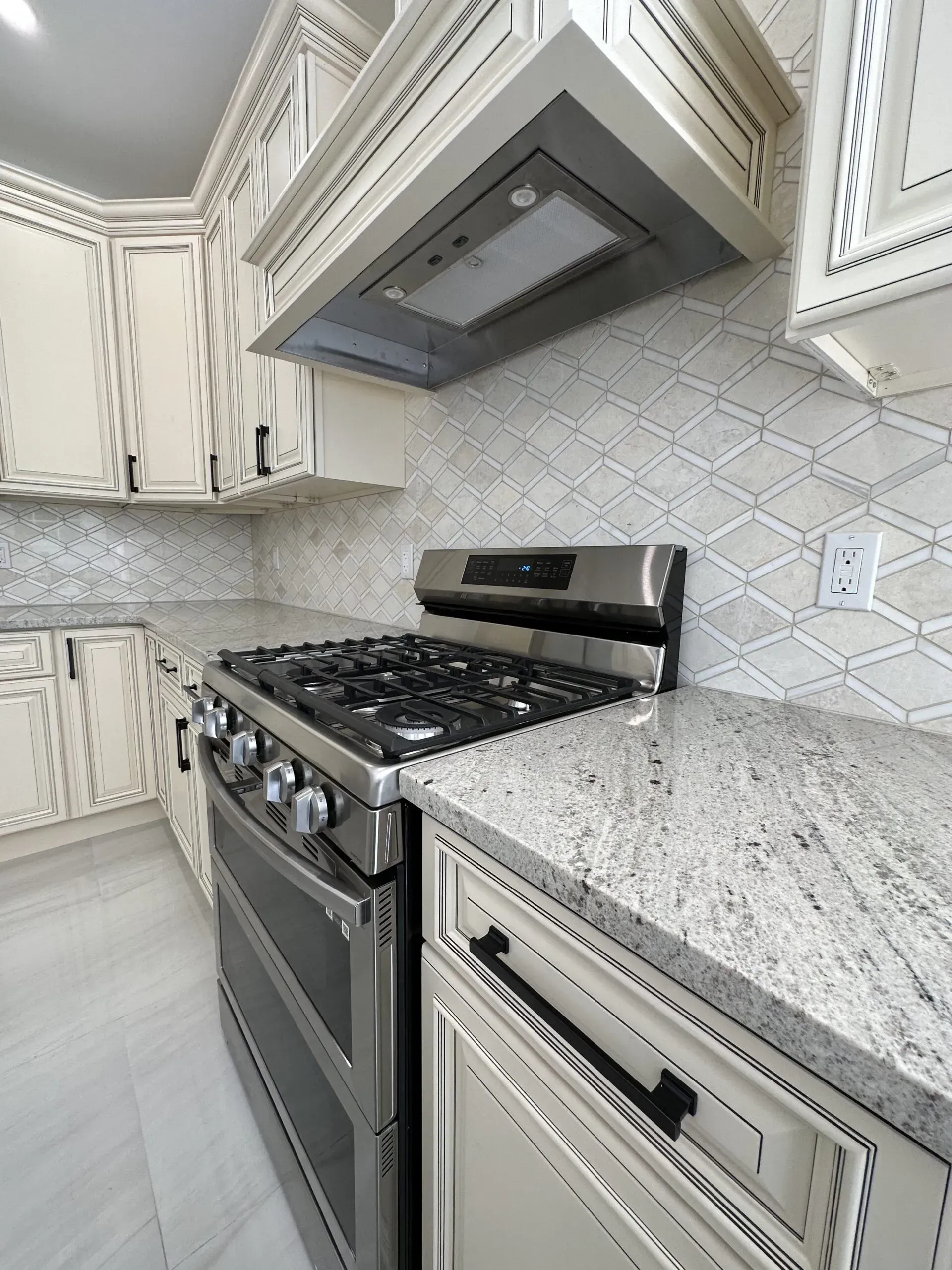 Modern kitchen with stainless steel gas range, granite countertop, and white patterned cabinets