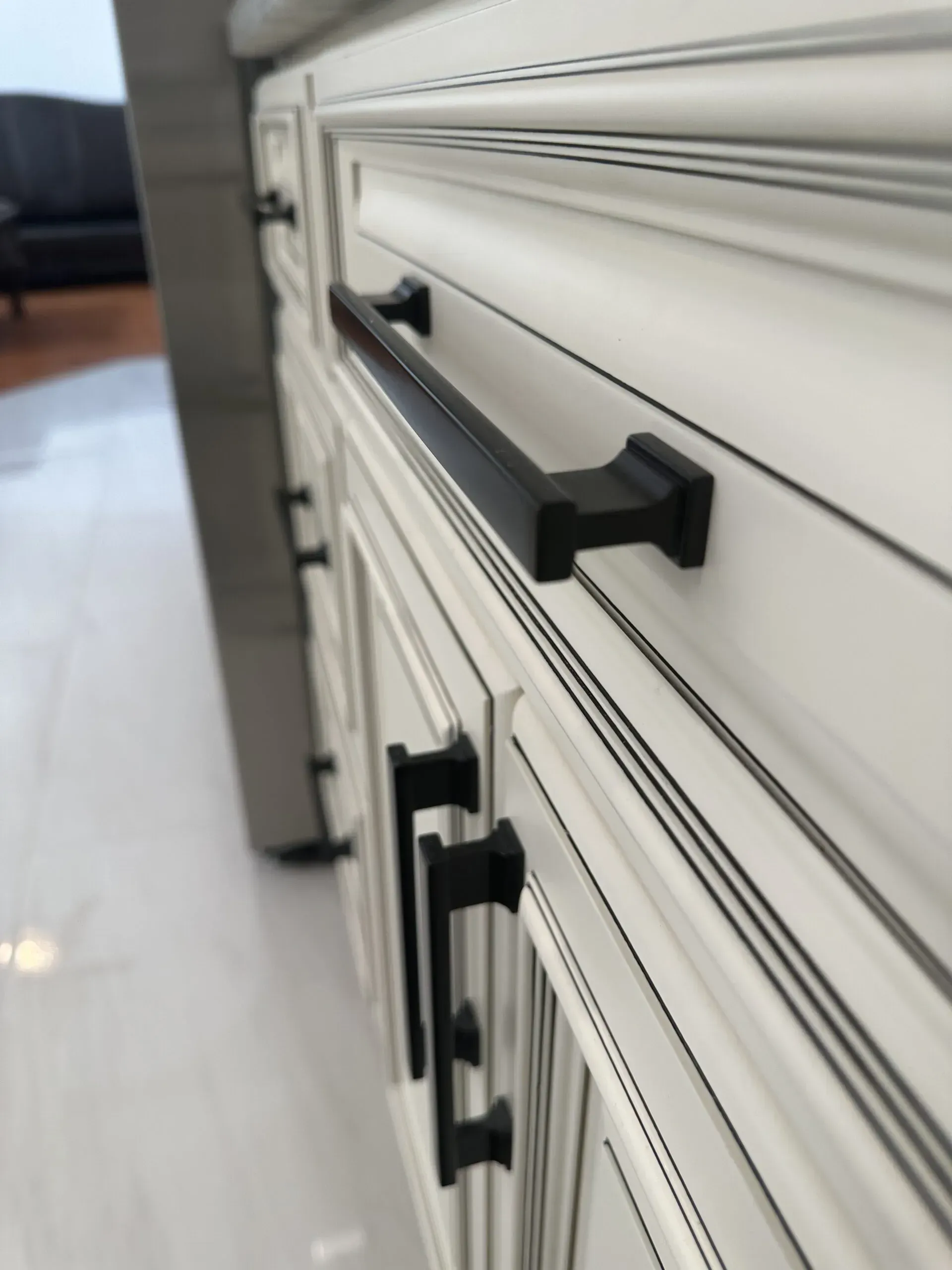 Close-up of black cabinet handles on a white drawer unit in a bright room