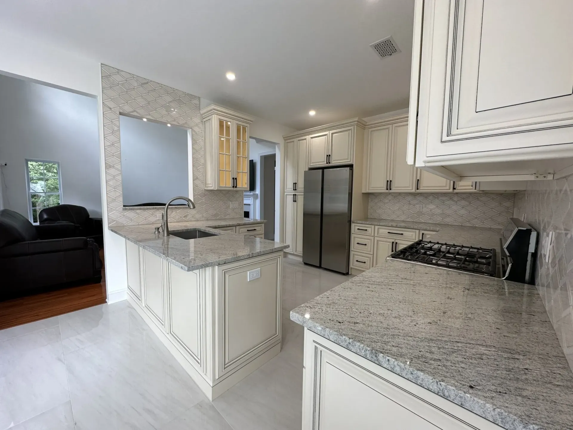 Bright kitchen with white cabinets, granite countertops, stainless steel fridge, and light wood floor