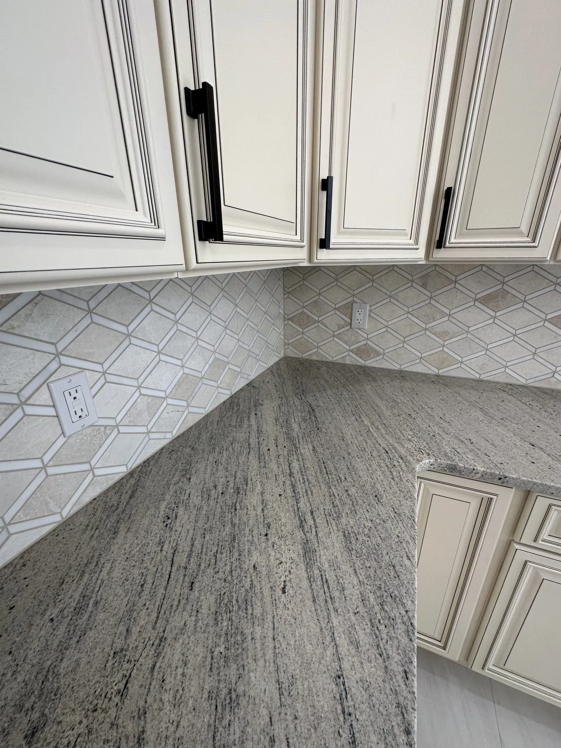 Upward view of a corner with white cabinet doors and gray patterned flooring or wall tiles.