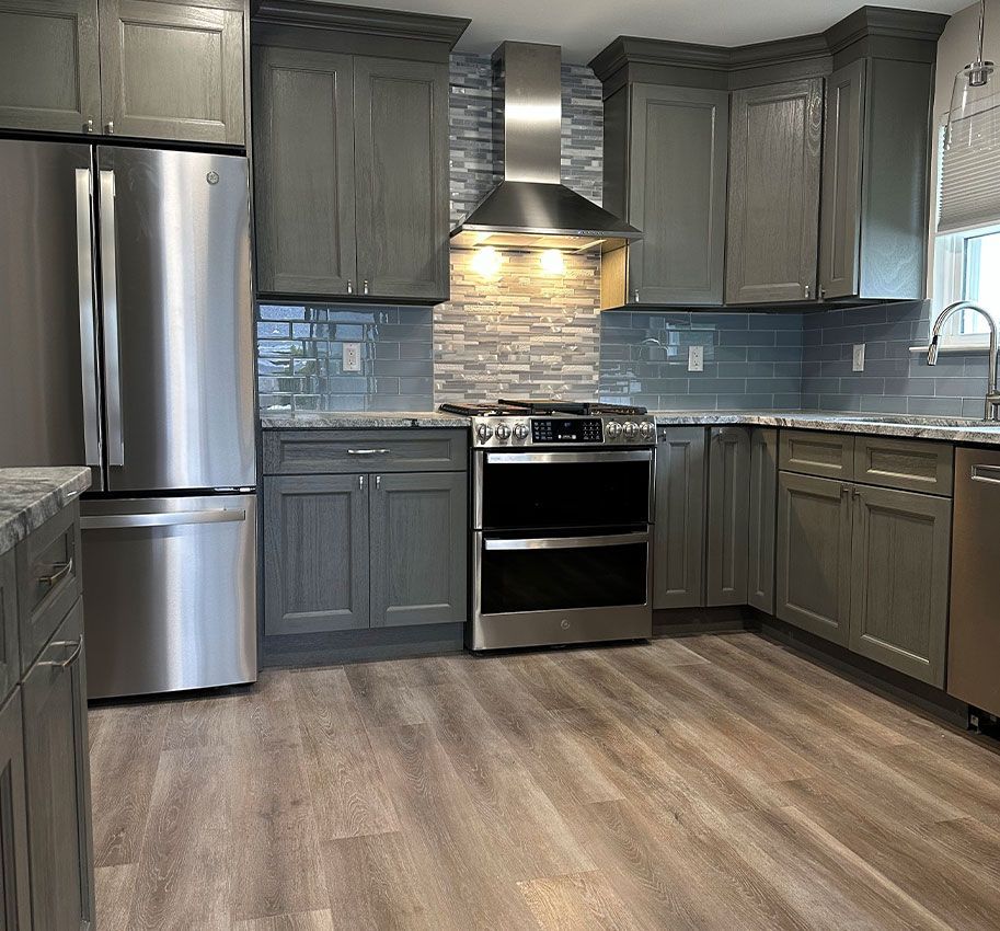 Modern kitchen with gray cabinets, stainless steel appliances, blue backsplash, and wood-look flooring