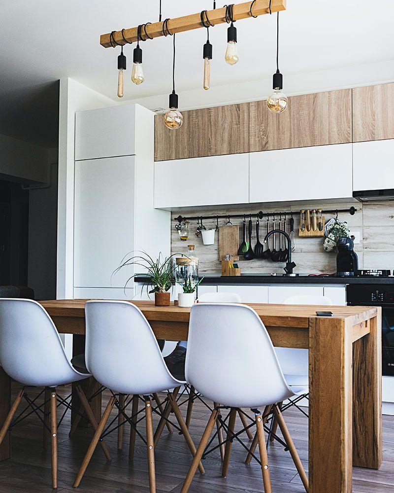 A kitchen with a wooden table and white chairs