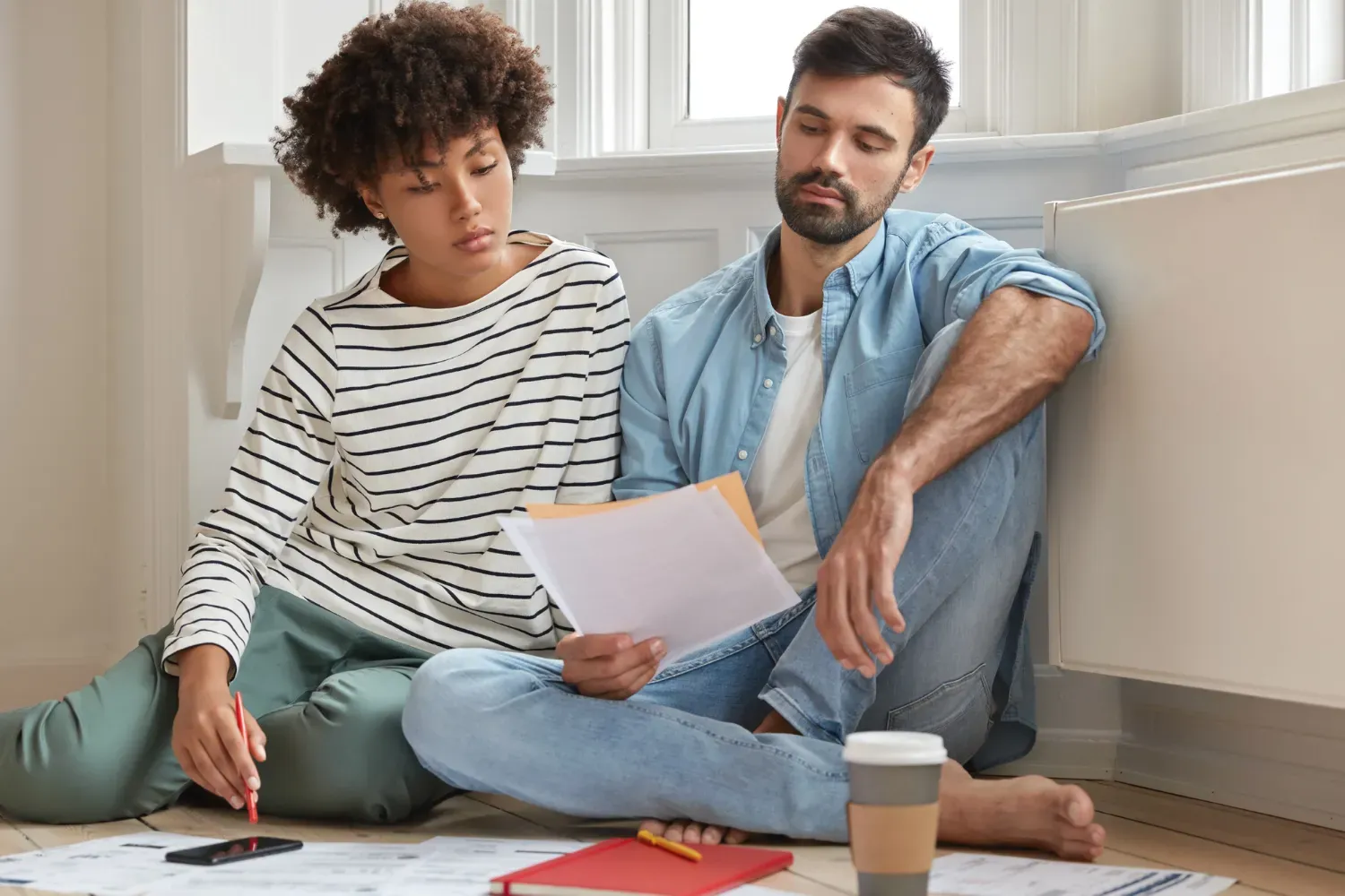 Un homme et une femme sont assis par terre et regardent des papiers.